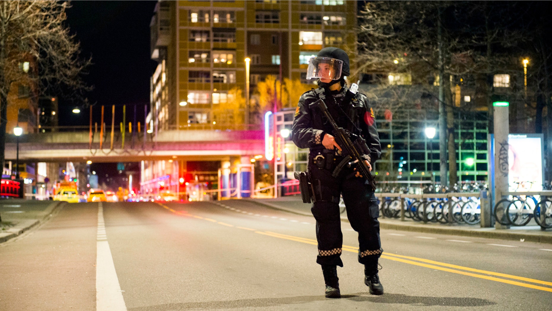 An officer stands guard as police cordon off a large area around a subway station on a busy commercial street Saturday night, April 8, 2017, after finding what they described as a "bomb-like" device, in Oslo, Norway.