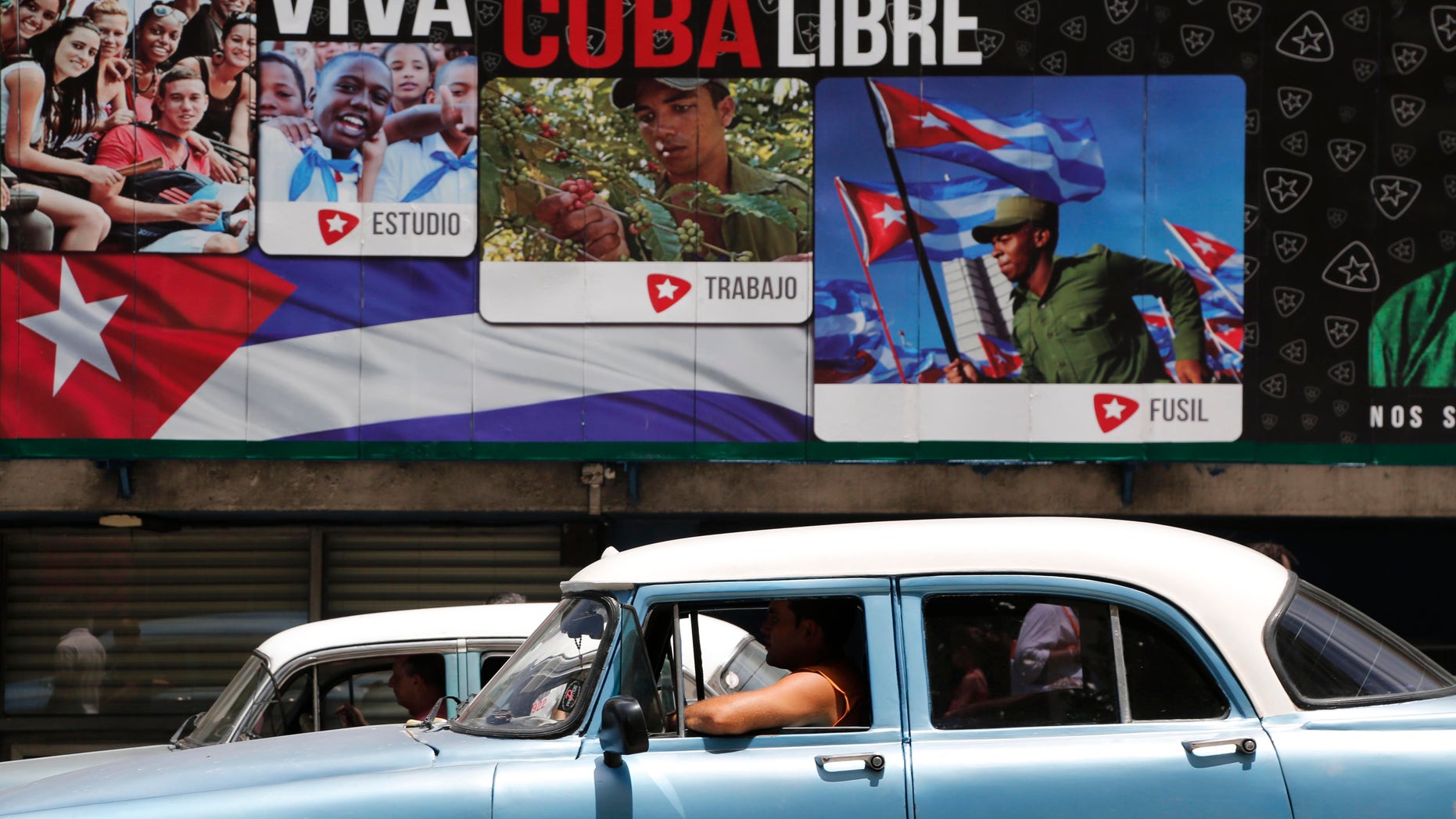 Un auto clásico estadounidense pasa frente a carteles que dicen "Viva Cuba libre" en La Habana, Cuba, el martes 16 de junio de 2015. El miércoles se cumplen seis meses desde que los presidentes Barack Obama y Raúl Castro sorprendieron al mundo al anunciar el fin de medio siglo de hostilidades entre Estados Unidos y Cuba. En Cuba, los envejecidos líderes temen un cambio rápido e incontrolado que les cueste el poder y pueda provocar inestabilidad en un país que teme a la violencia y la desigualdad que afectan a sus vecinos. Ese temor se ve acrecentado por la larga historia de intentos estadounidenses de derrocar a Castro y a su hermano Fidel. (AP Foto/Desmond Boylan)