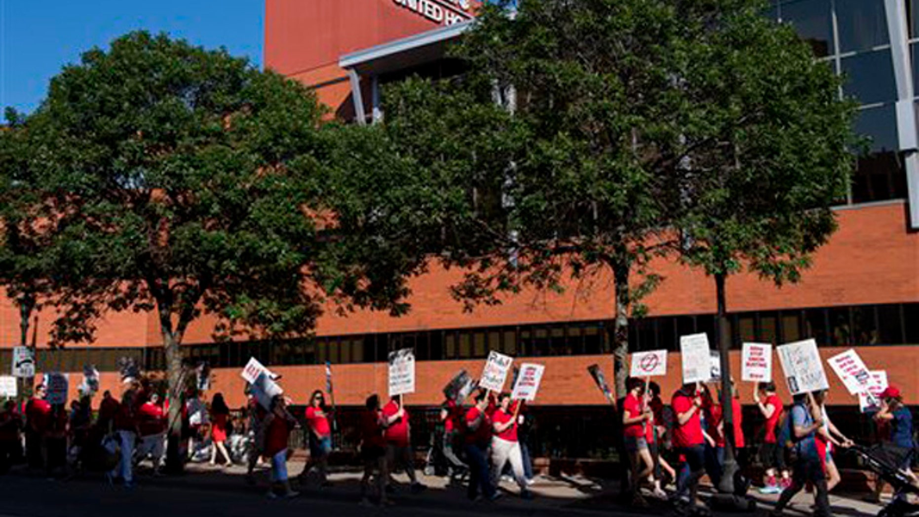 Picketers walk in front of United Hospital in St. Paul, Minn., Sunday, June 19. 2016.