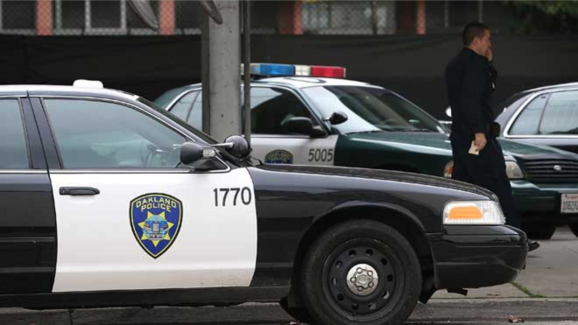OAKLAND, CA - DECEMBER 06: An Oakland Police officer walks by patrol cars at the Oakland Police headquarters on December 6, 2012 in Oakland, California. Oakland City officials have come to an agreement to forfeit broad power over the Oakland Police Department to a court-appointed director to avoid federal takeover. The new compliance director would have the power to seek approval from a judge to fire the police chief. (Photo by Justin Sullivan/Getty Images)