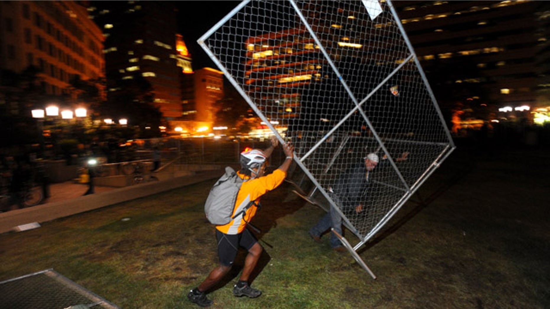 Oct. 26, 2011: An Occupy Oakland protester topples a fence outside city hall in Oakland, Calif. The fence was meant to keep out protesters who had camped out for the past two weeks before police raided the plaza early Tuesday.