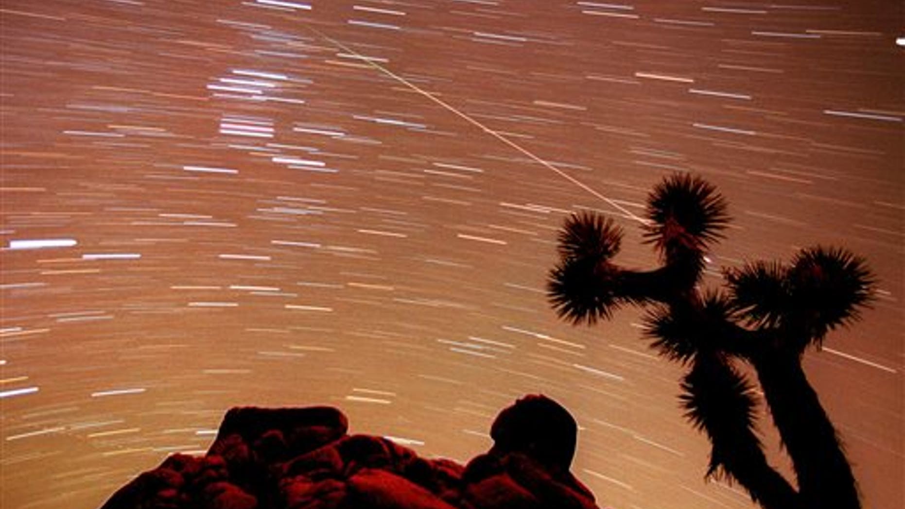FILE - In this Nov. 17, 1998, file time exposure photo, a meteor streaks through the sky over Joshua trees and rocks at Joshua Tree National Monument in Southern California's Mojave Desert. President Barack Obama is granting national monument status to nearly 1.8 million acres of scenic California desert wilderness, including land that would connect what is now Joshua Tree National Park to other established national monuments and national parks in the area. Obama, in California this week for a fund-raising swing, plan to make the announcement Friday, Feb. 12, 2016. (AP Photo/Reed Saxon, File)