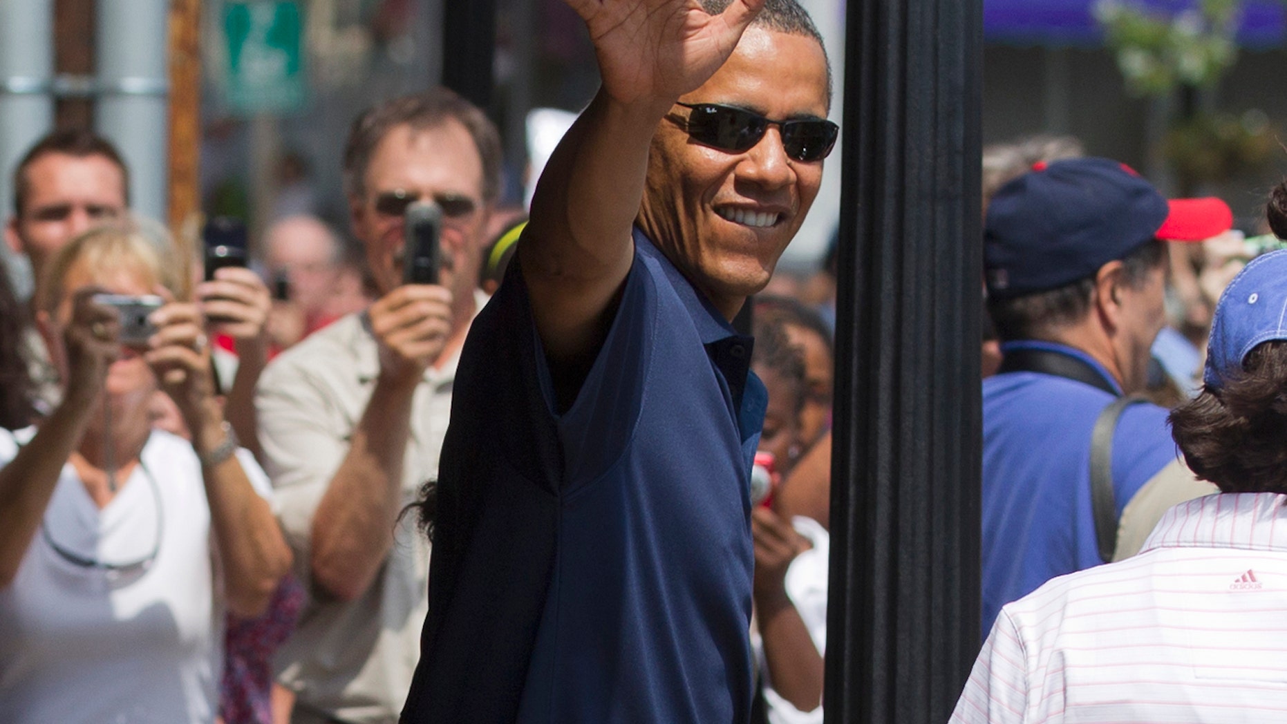 President Barack Obama, with his daughters Malia Obama and Sasha Obama, not seen, waves as they leave the Bunch of Grapes book store in Vineyard Haven, Mass., Friday, Aug. 19, 2011, during a family vacation. (AP Photo/Carolyn Kaster)