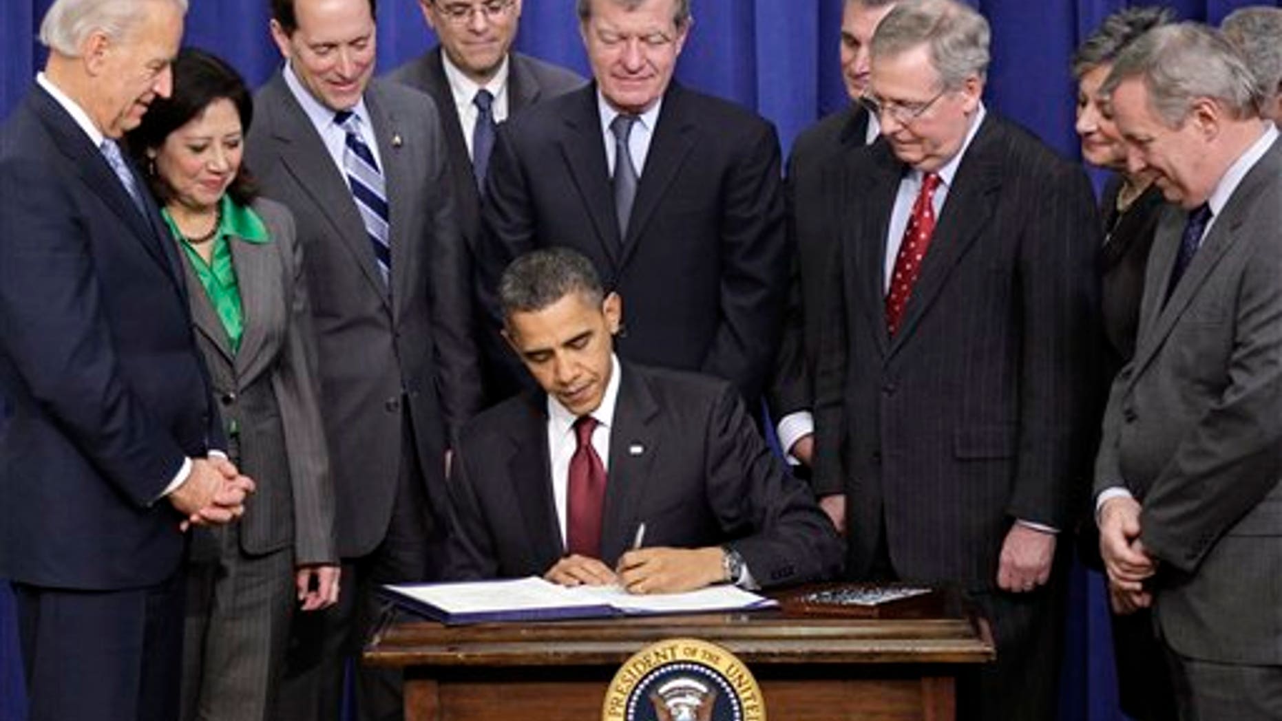 FILE: In this Dec. 17, 2010, photo, Senate Minority Leader Mitch McConnell looks over President Obama's shoulder as Republican and Democratic lawmakers witness the president sign the tax package extending Bush-era tax rates for families at all income levels.
