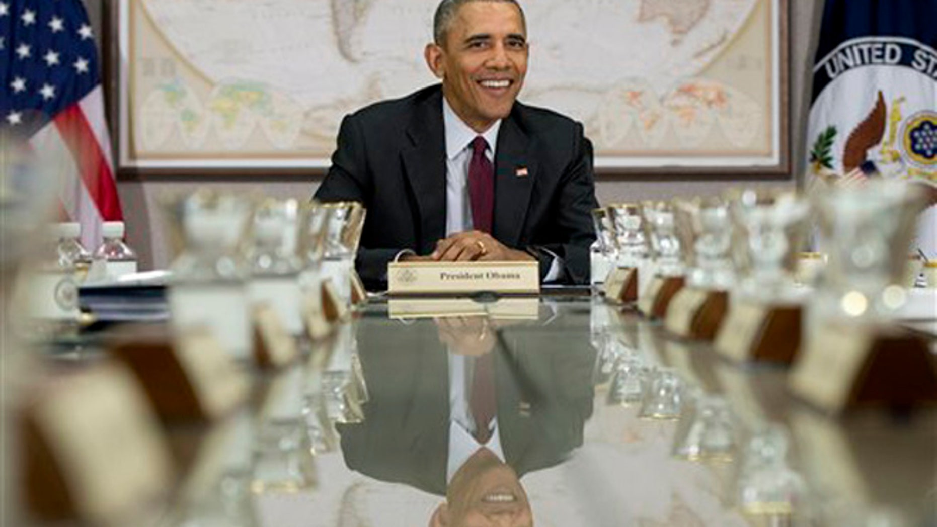 President Barack Obama is reflected in the conference table before a meeting of his National Security Council (NSC) at the State Department in Washington, Thursday, Feb. 25, 2016. The meeting is to focus on the global campaign to degrade and destroy ISIL as well as Syria and other regional issues. (AP Photo/Carolyn Kaster)