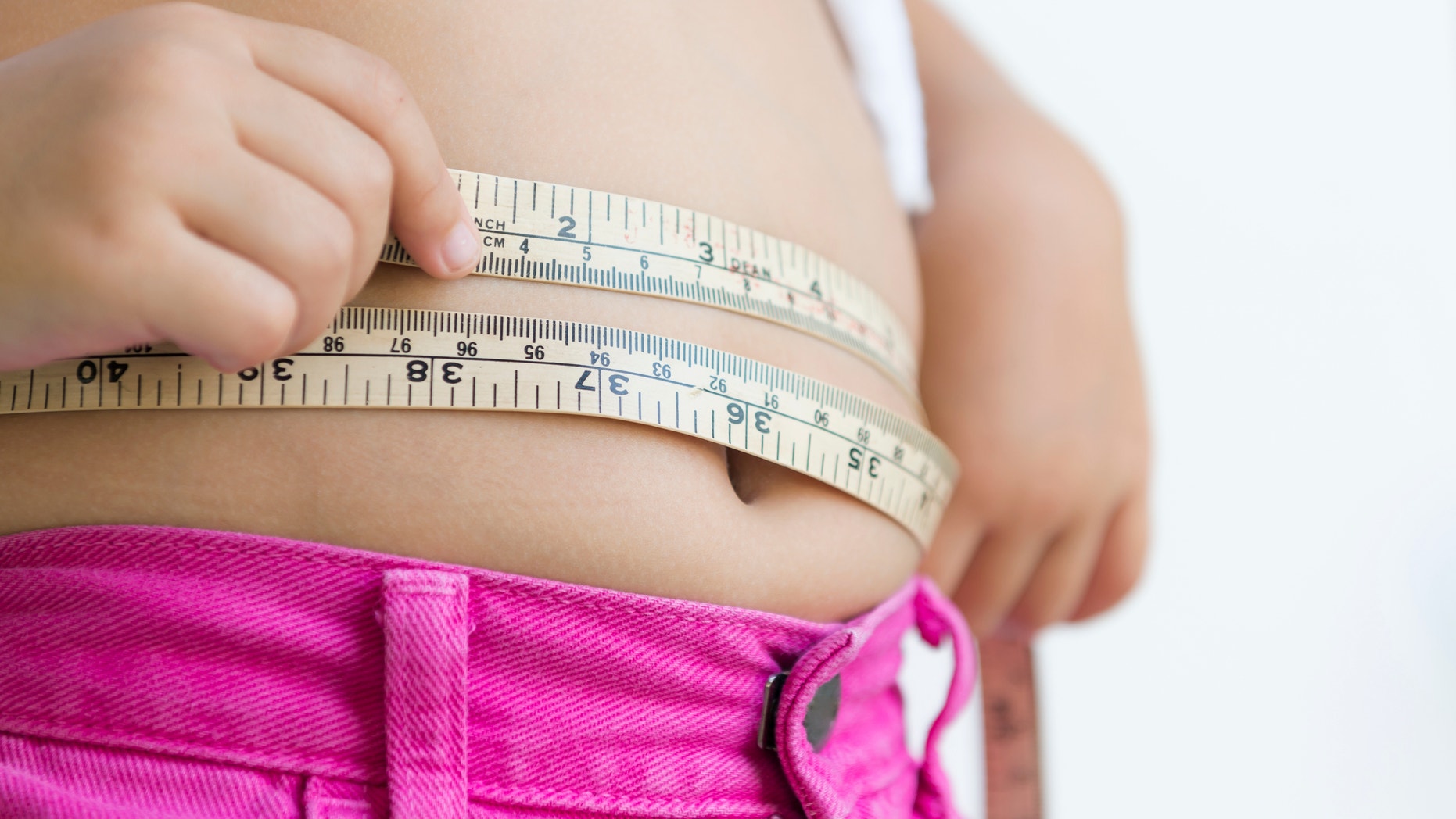 cute girl measuring her belly with measurement tape at home
