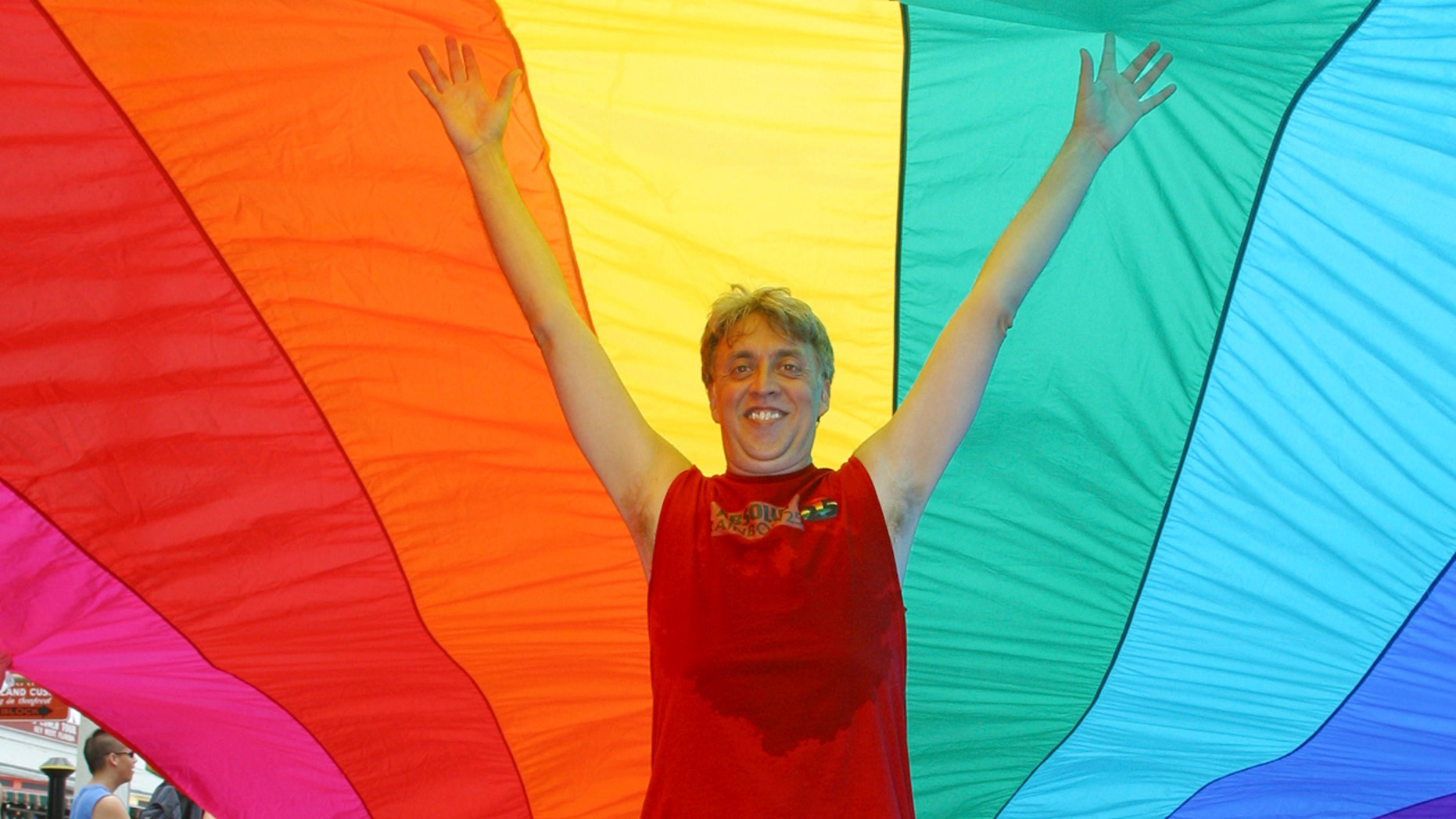 In this June 15, 2003, file photo, Gilbert Baker stands under a 1 1/4-mile-long rainbow flag on Duval Street in Key West, Fla. Baker, the creator of the rainbow flag that has become a widely recognized symbol of gay rights has died at age 65.