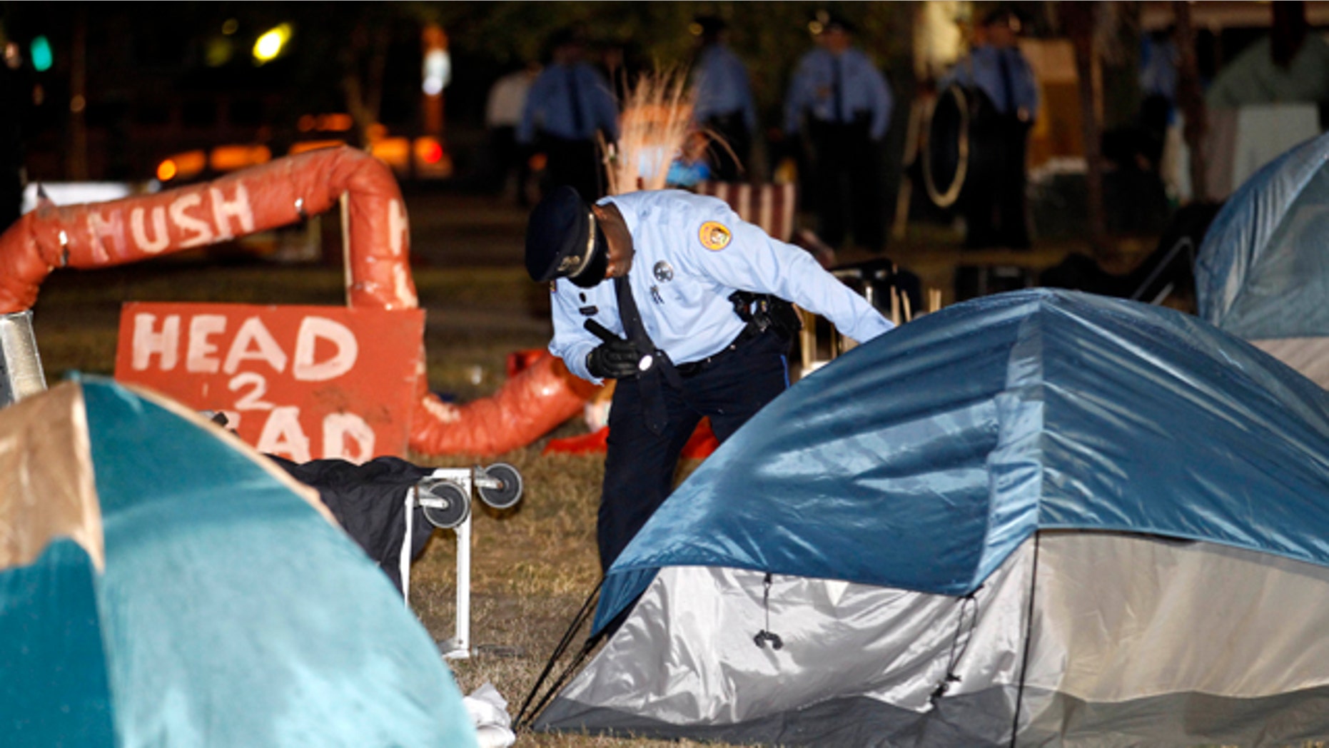 Dec. 6, 2011: A New Orleans police officer checks a tent for people as they clear out the Occupy New Orleans encampment in Duncan Plaza across from City Hall in New Orleans.
