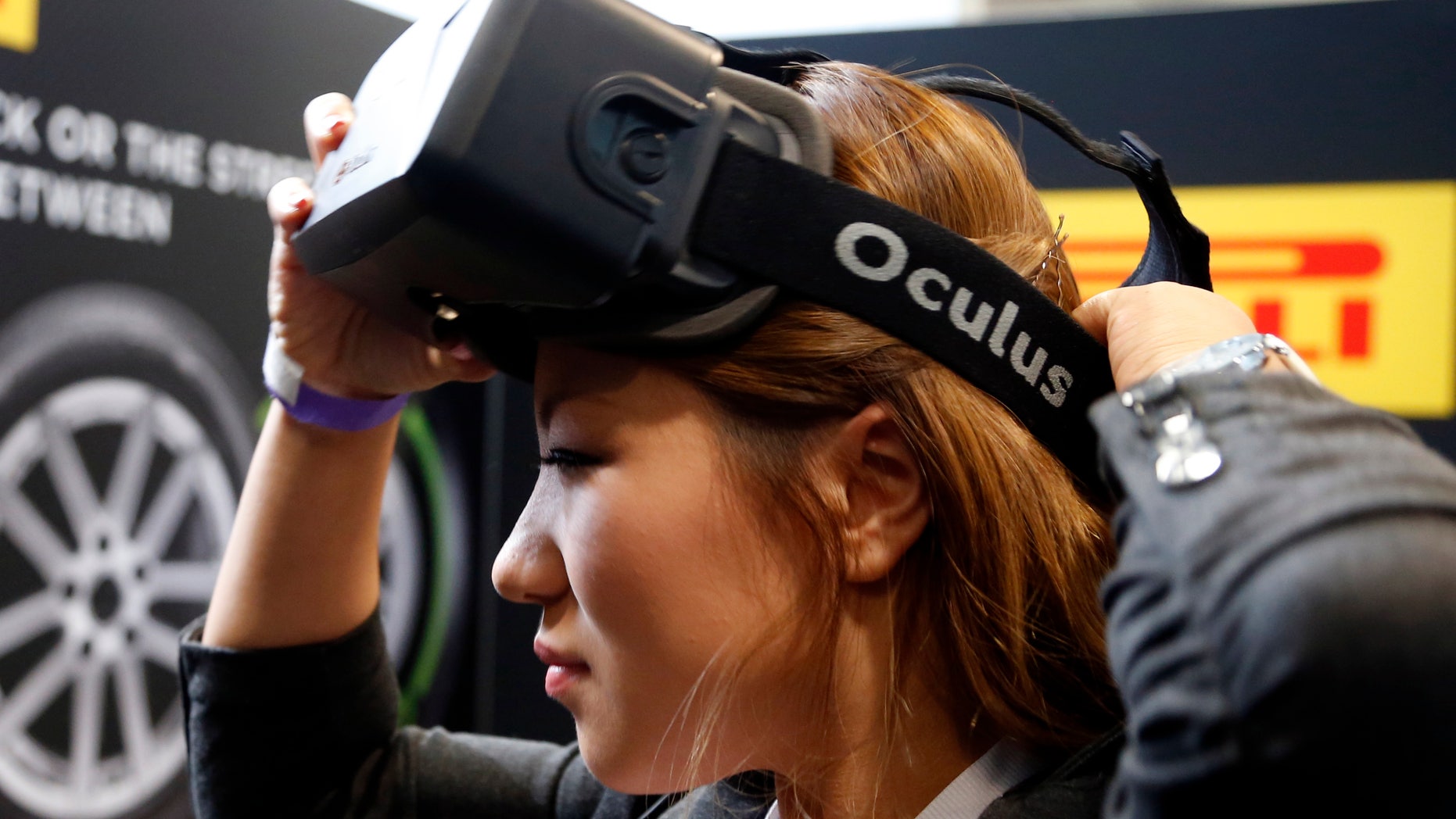 A woman puts on an Oculus virtual reality headset during preparations for the 2014 LA Auto Show in Los Angeles, California November 18, 2014. REUTERS/Lucy Nicholson