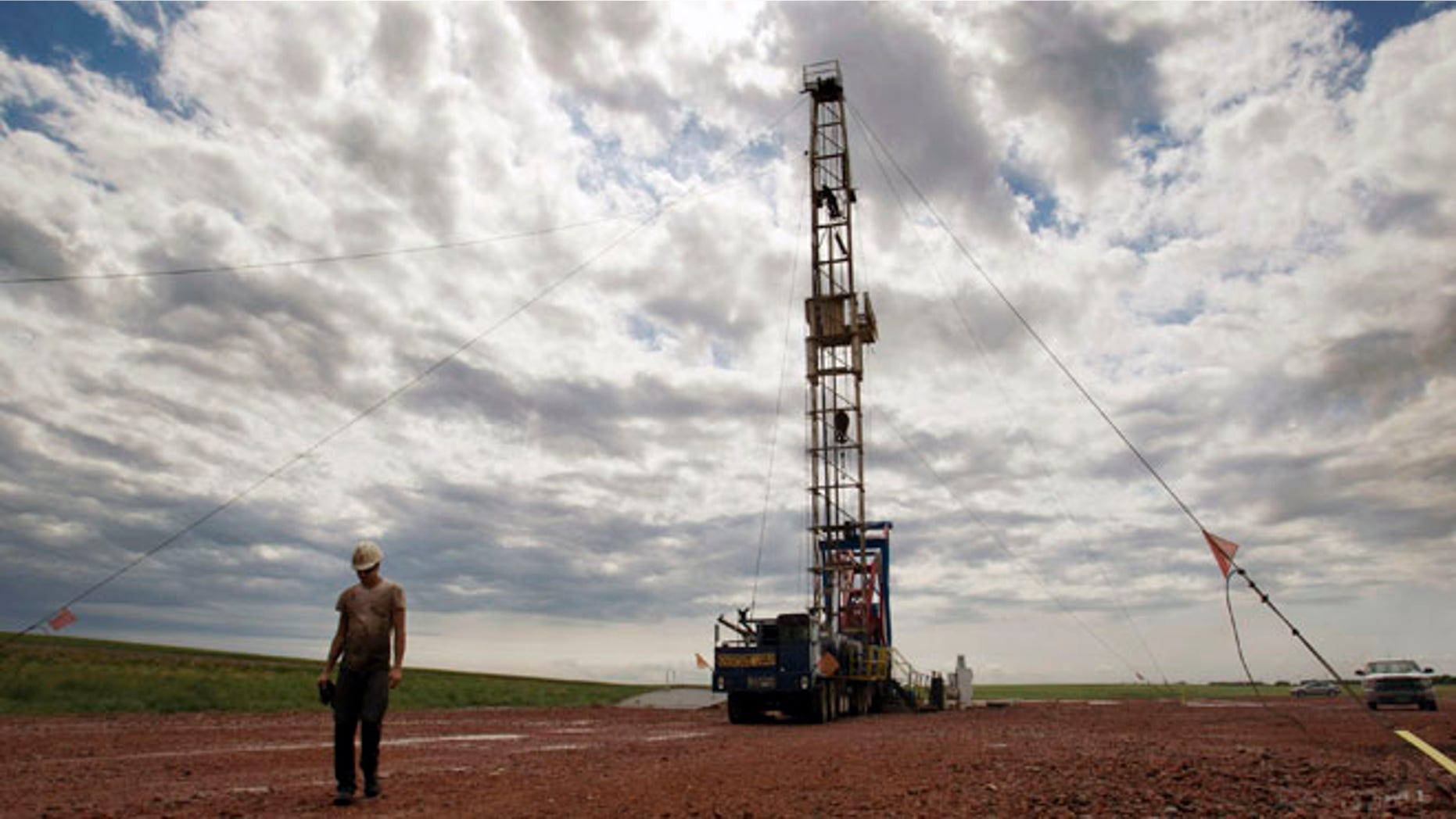 July 26, 2011: A worker walks by an oil derrick outside of Williston, N.D. Relief could be on the horizon for strapped public services in the Northern Plains' booming oil patch, as elected leaders in Montana and North Dakota move to steer more money into the region during the states' upcoming legislative sessions.
