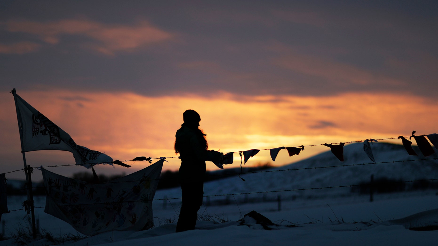 A woman watches the sunset at the Oceti Sakowin camp where people have gathered to protest the Dakota Access oil pipeline in Cannon Ball, N.D., Friday, Dec. 2, 2016.