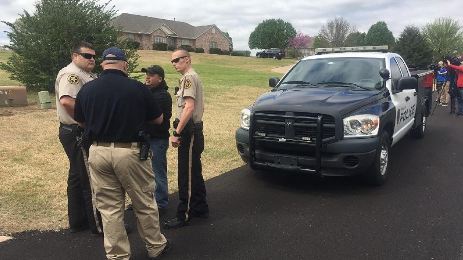Sheriff's deputies gather outside a home in Broken Arrow, Okla., where three intruders were shot and killed Monday, March 27, 2017.