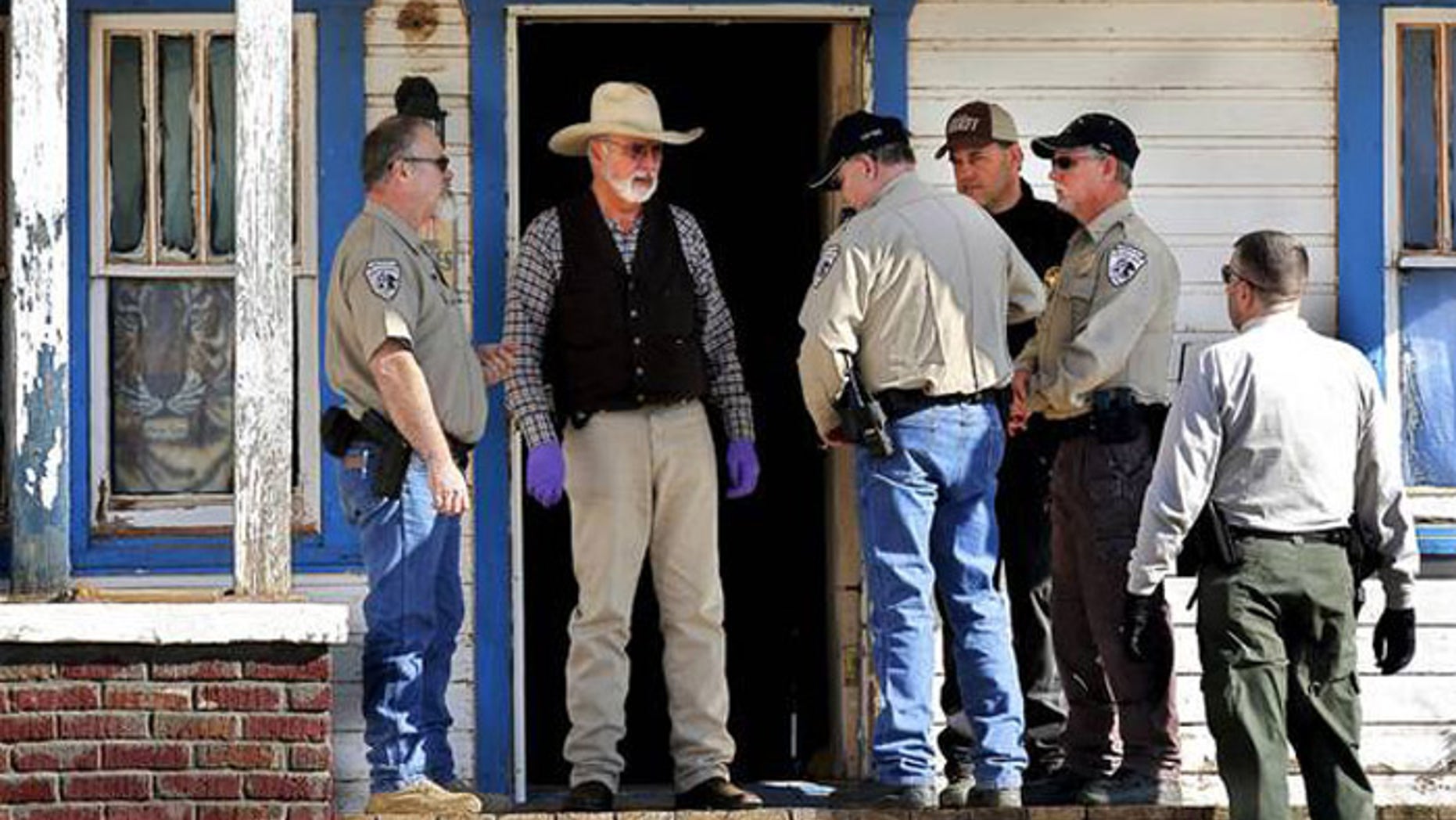 Agents from the Oklahoma State Bureau of Investigation and Washita County sheriff’s deputies talk on the front porch of the house where Sentinel Police Chief Louis Ross was shot four times.(Courtesy: The Oklahoman)