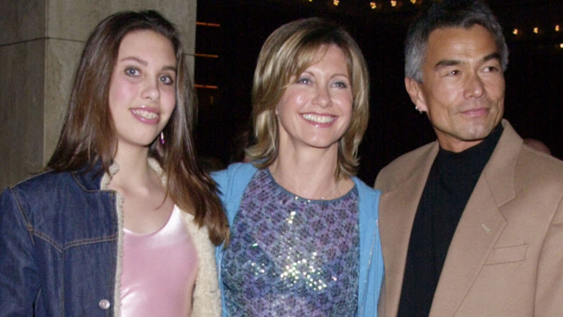 Singer and actress Olivia Newton-John (C) poses with her daughter Chloe and Patrick McDermott upon arriving February 26, 2001 for the opening night of "Mamma Mia!" at the Los Angeles Shubert Theatre. REUTERS