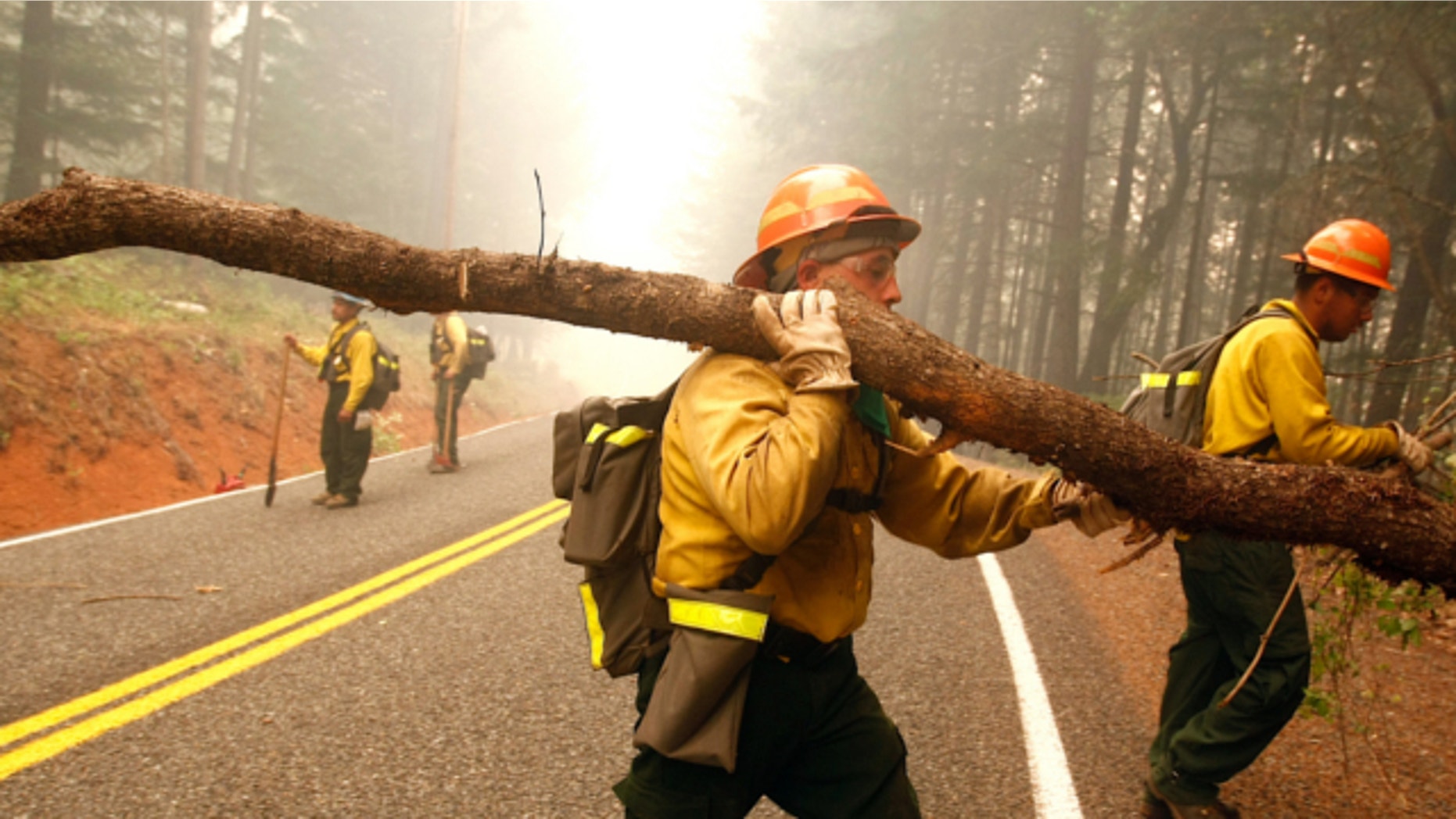 July 31, 2013: Dalles, Ore. firefighters Mario Carmona, middle, and Ismael Vega, right, help clear brush and trees near a home in Wolf Creek, Ore.