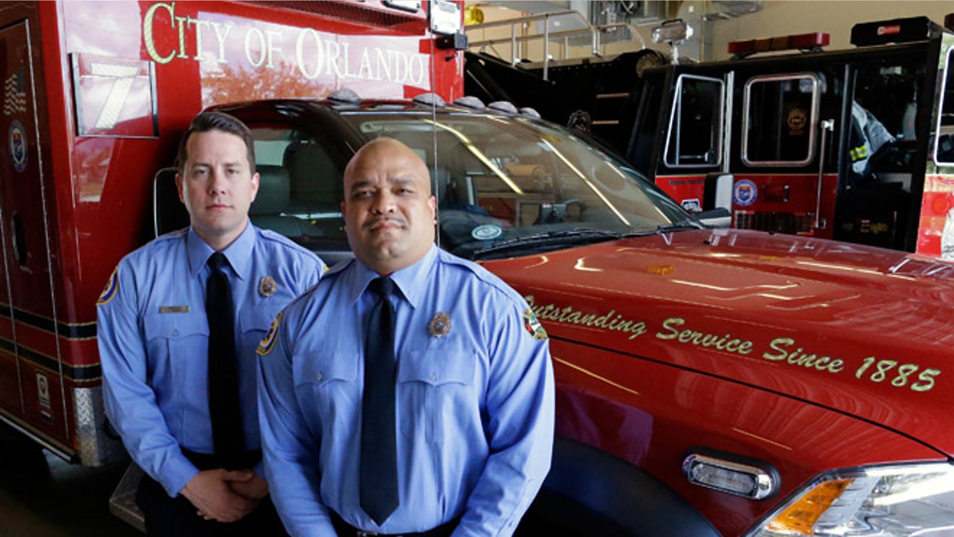 In this Thursday, June 30, 2016 photo, Josh Granada, left, and Carlos Tavarez the first paramedic-firefighters to respond to the Pulse nightclub shooting stand by their emergency vehicle at their fire station in Orlando, Fla. They made five trips with 13 victims to a hospital emergency room just a few blocks away the evening of the shooting.(AP Photo/John Raoux)