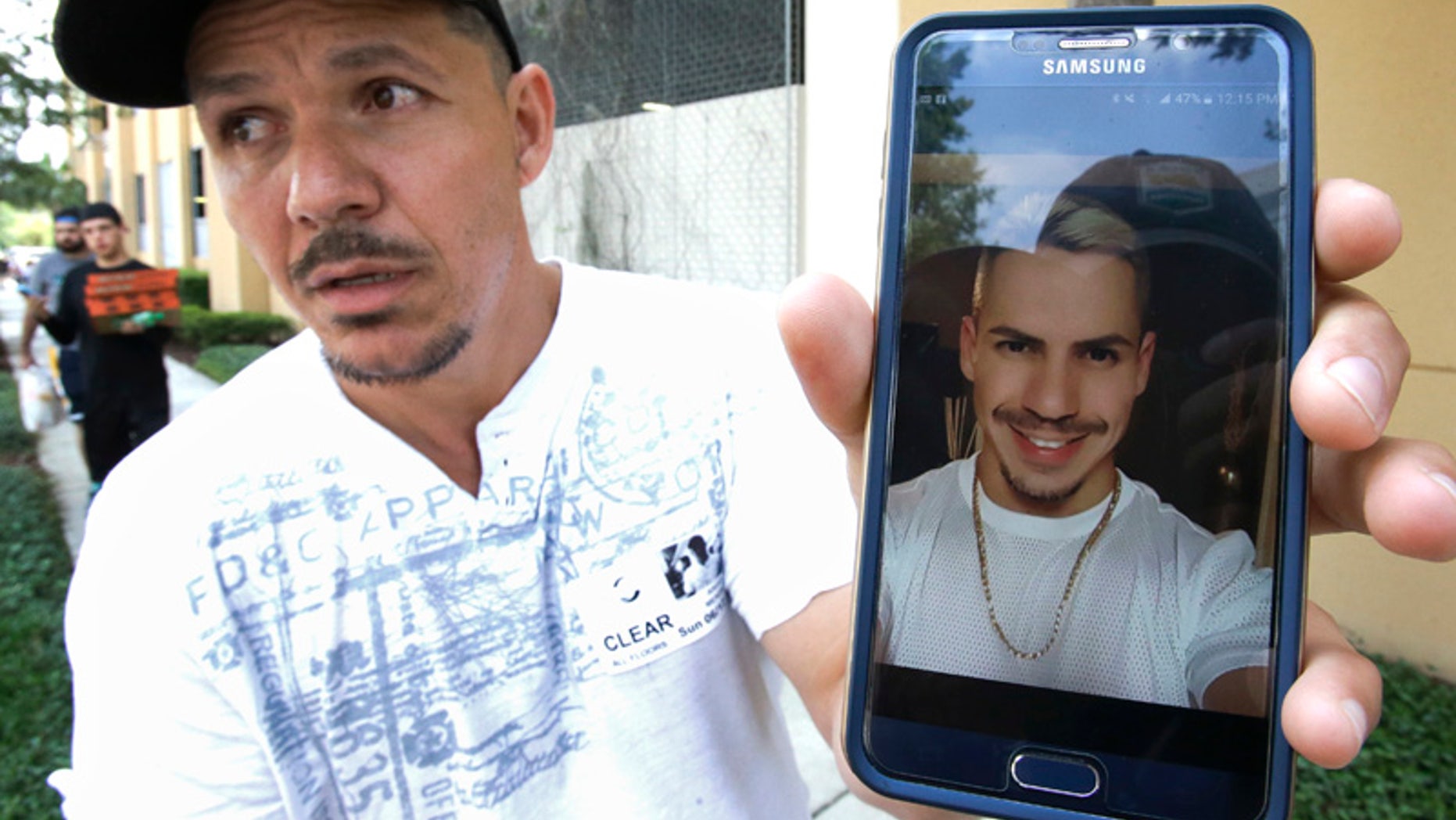Angel Mendez, standing outside the Orlando Regional Medical Center, holds up a cell phone photo trying to get information about his brother Jean C. Mendez that was at the Pulse Nightclub where a shooting involving multiple fatalities occurred, Sunday, June 12, 2016, in Orlando, Fla. (AP Photo/John Raoux)