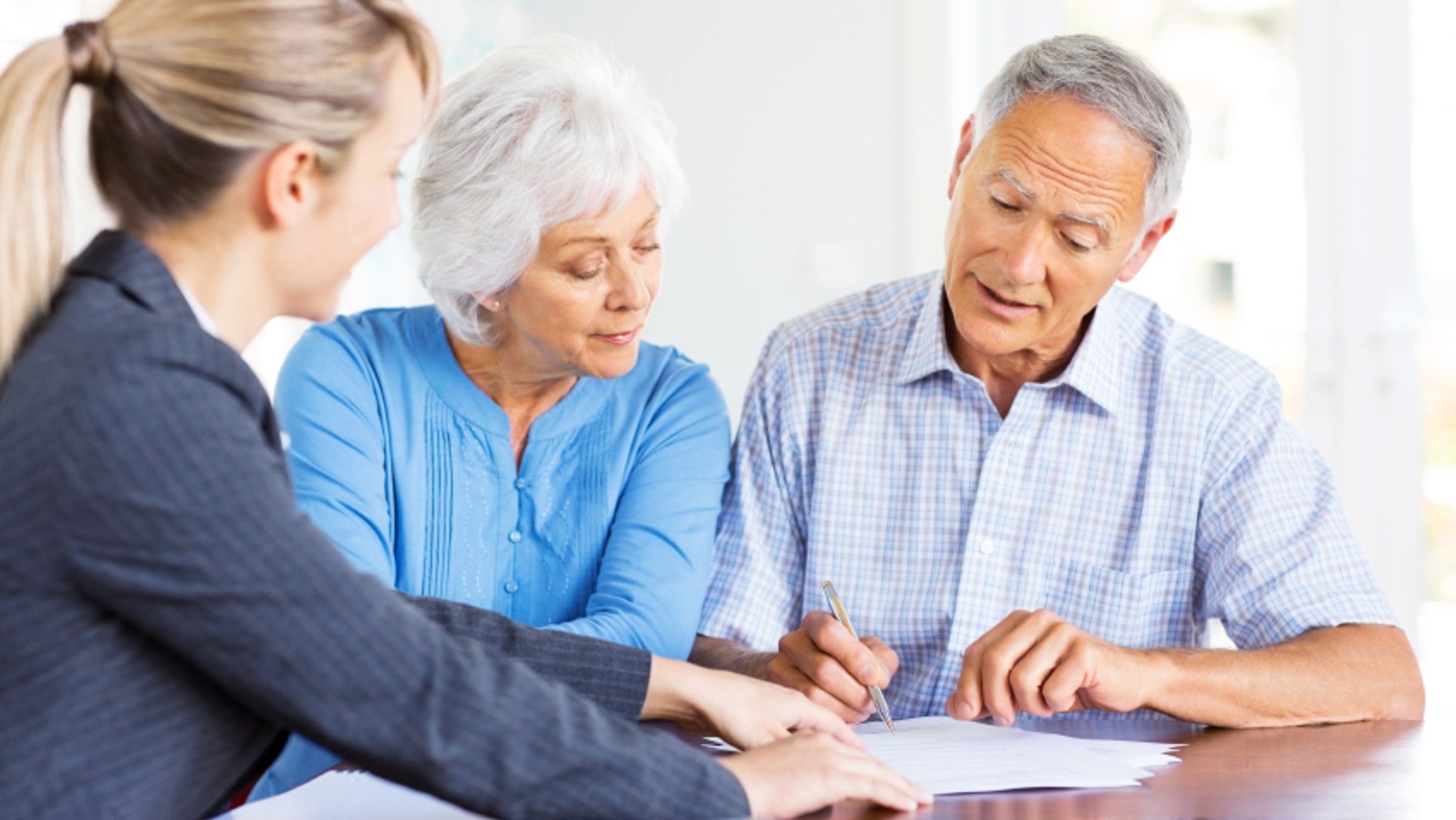 Financial advisor explaining investment plans to senior couple at home. Horizontal shot.