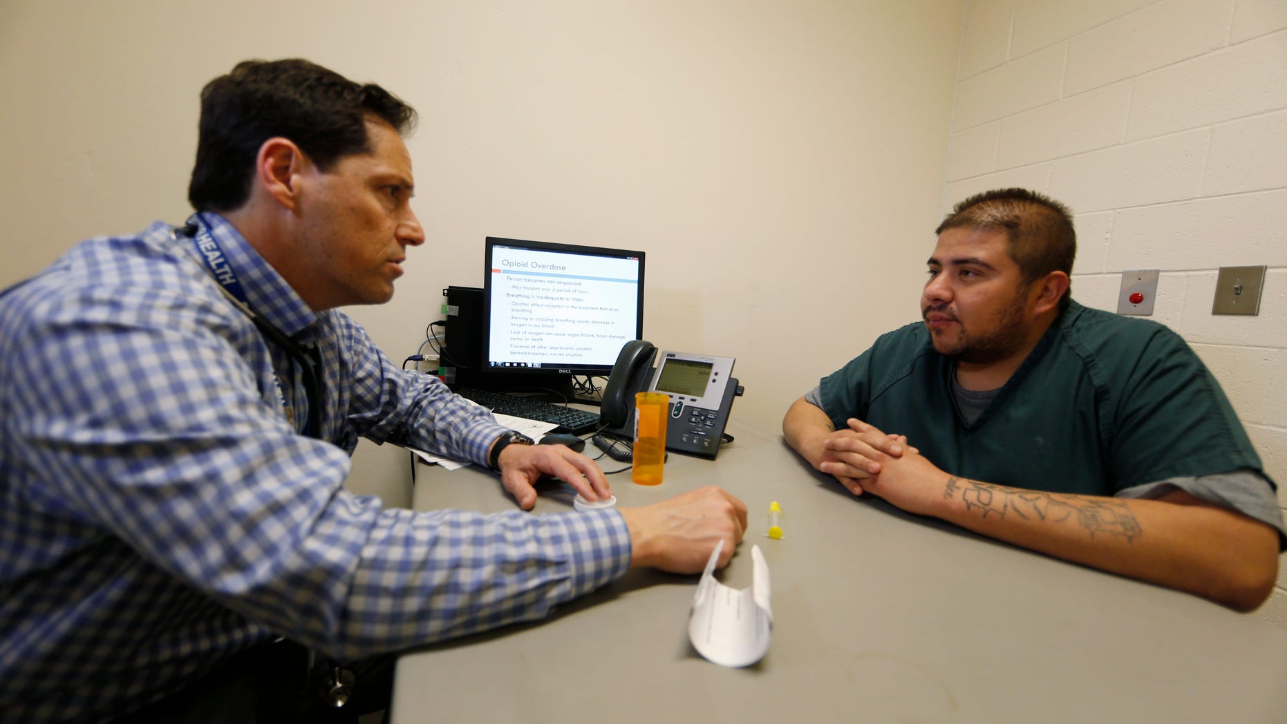 In this Tuesday, March 1, 2016, photograph, Dr. Josh Blum, left, confers with inmate Lee Gonzales at the Denver County Jail in downtown Denver. Jails and correction agencies across the country such as Denver are teaching soon-to-be-released inmates how to use the heroin overdose antidote called naloxone, either to save others and sometimes themselves. (AP Photo/David Zalubowski)