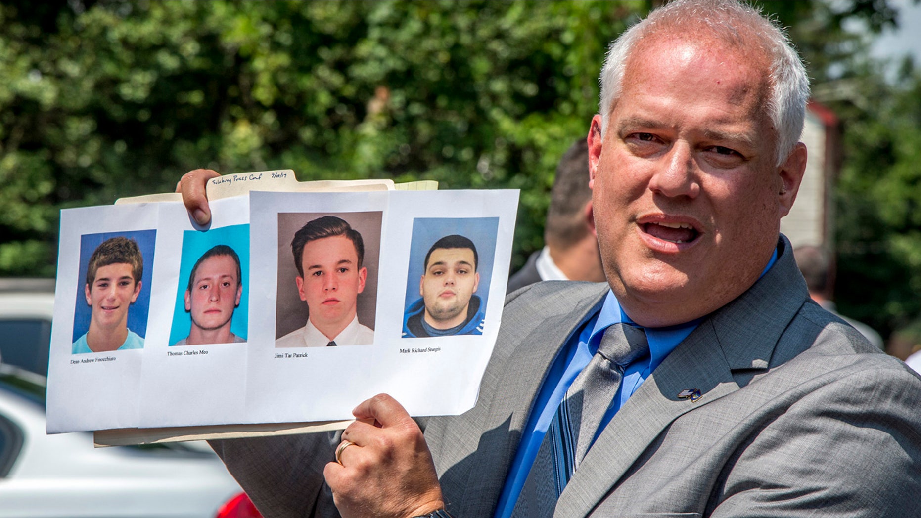 Bucks County District Attorney Matthew Weintraub holds up photos of four men during a news conference in Solebury Township, Pa.