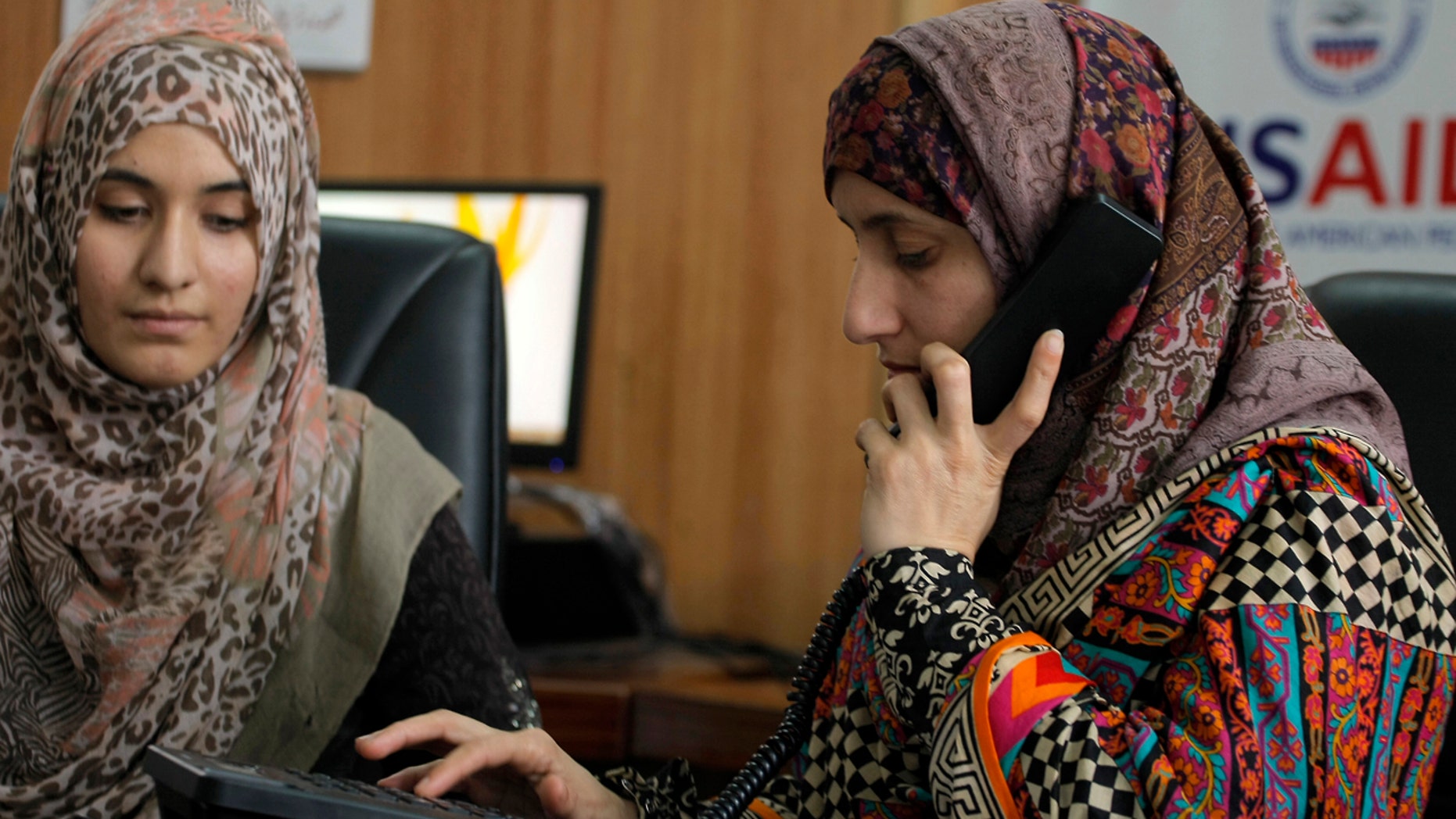 Pakistani lawyer Shandana Naeem, right, listens to a caller to a domestic violence helpline with her colleague Nayab Hassan at their office in Peshawar, Pakistan, on March 28, 2017.