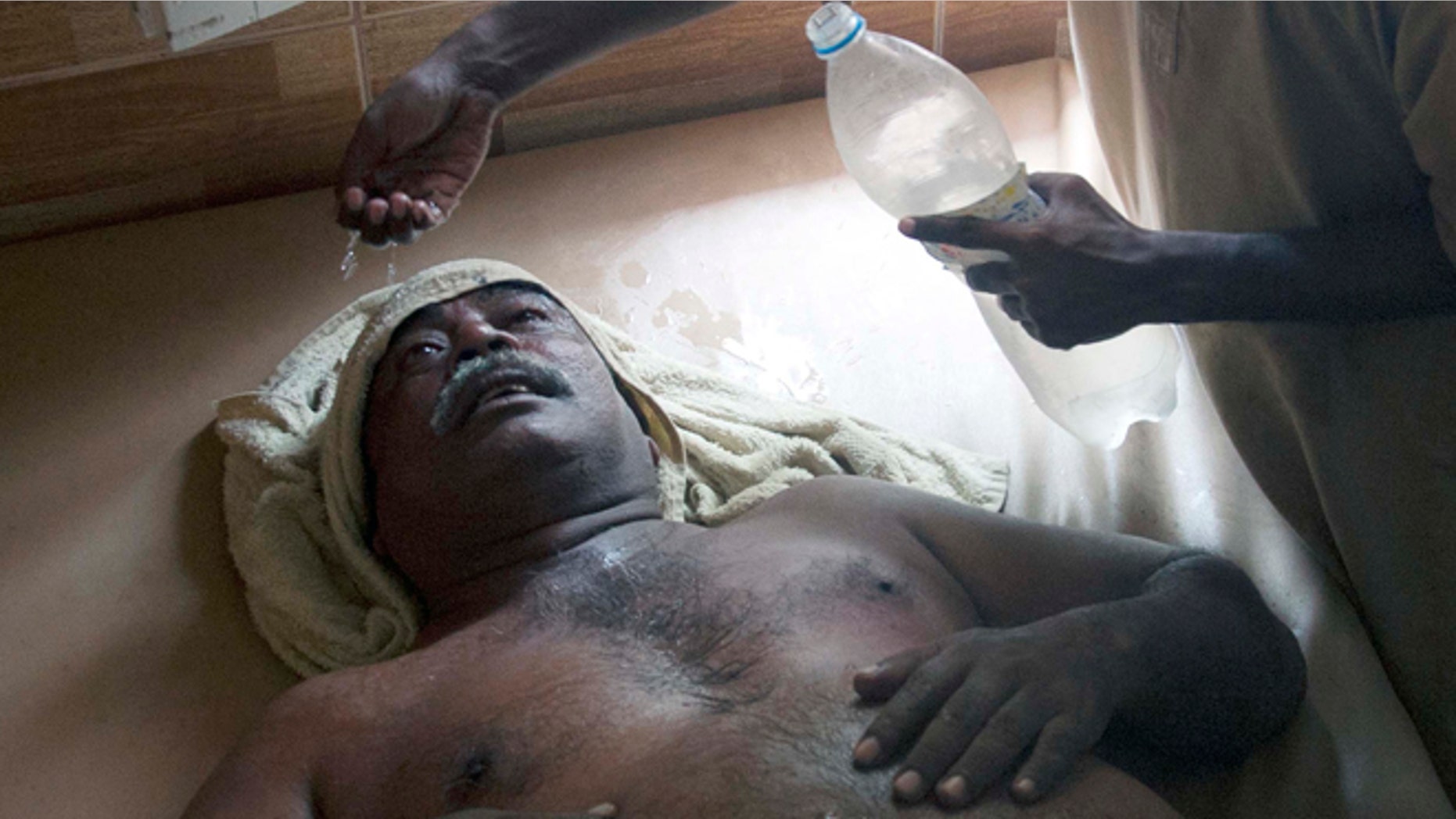 June 23, 2015: A Pakistani boy sprinkles water on his father who is suffering from heatstroke in Karachi, Pakistan. A scorching heat wave across southern Pakistan's city of Karachi has killed more than 400 people, authorities said Tuesday, as morgues overflowed with the dead and overwhelmed hospitals struggled to aid those clinging to life.
