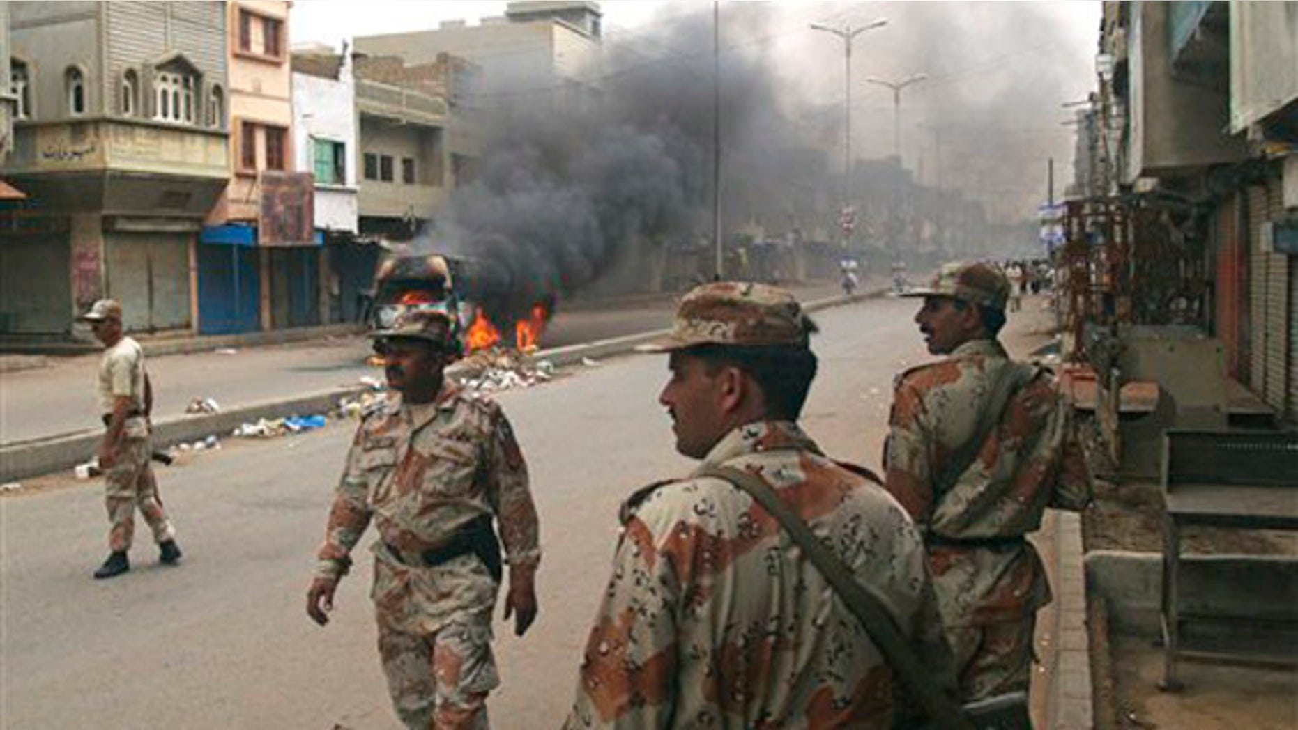 Pakistani para military troops gather near a vehicle set on fire by angry mob following the killing of a local leader of the Muttahida Quami Movement in Pakistan on Tuesday, Aug. 3, 2010. Gunmen killed dozens of people in Pakistan's largest city after the assassination of a lawmaker.