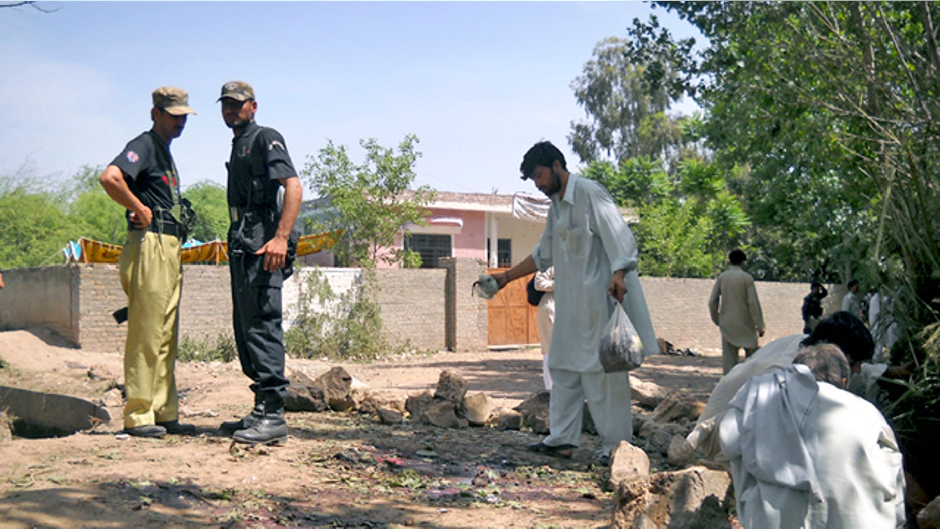 Pakistani police officers and rescue worker inspect the site of homicide bombing in Kacha Pukka area near Kohat, Pakistan. (AP)