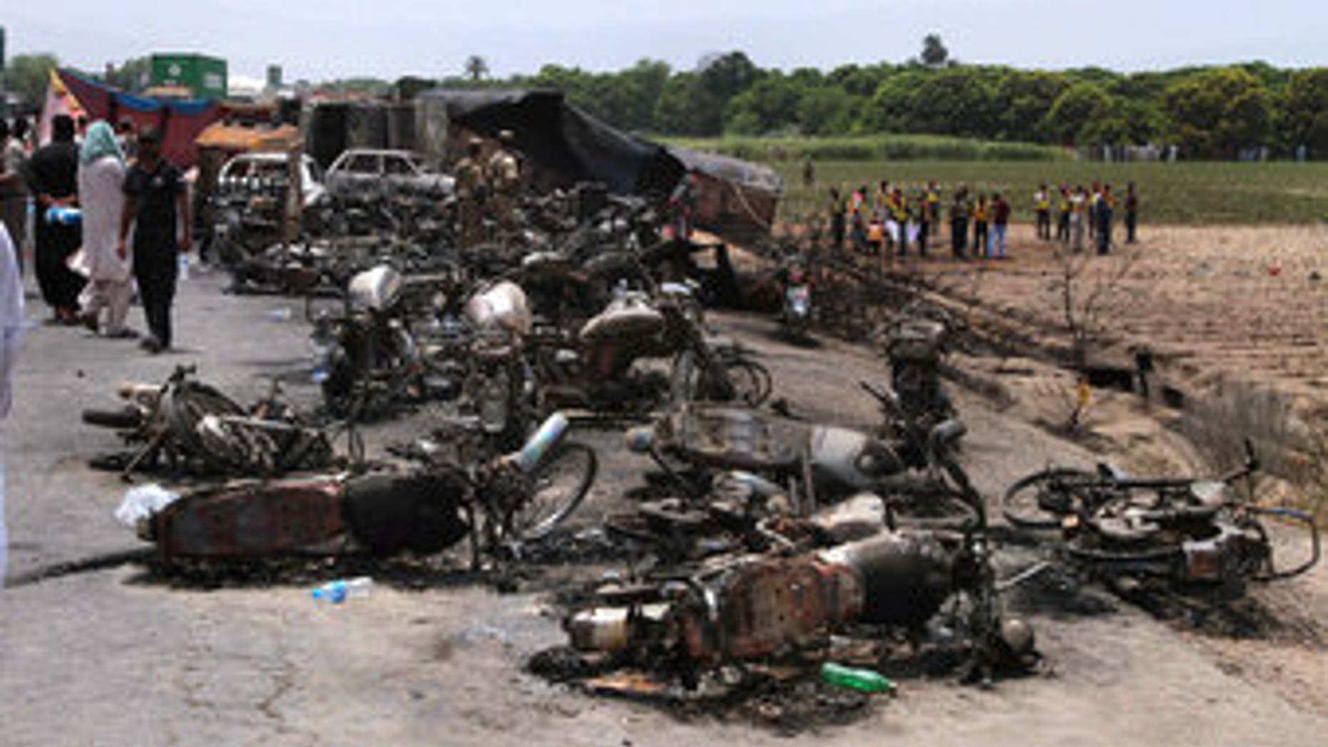 Pakistan Army soldiers stand guard while rescue workers examine the site of an oil tanker explosion at a highway near Bahawalpur, Pakistan, on June 25, 2017.