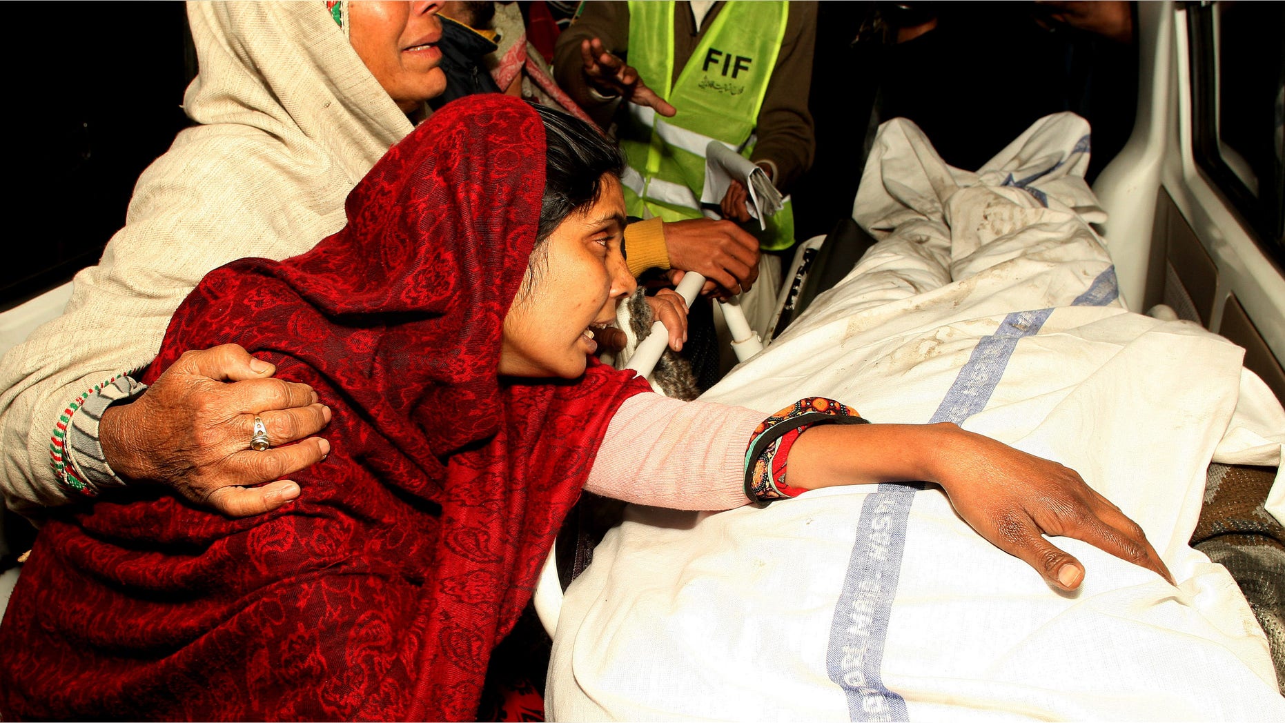 Dec. 29, 2014: A Pakistani woman mourns over the dead body of a family member after a fire broke out in a building, in Lahore, Pakistan