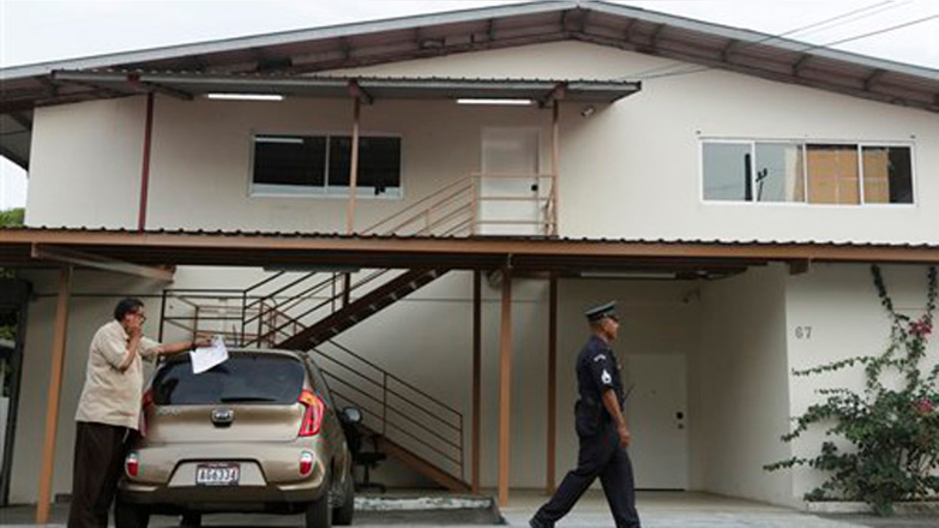 A Panamanian police officer and private security guard stand outside a warehouse used by the Mossack-Fonseca law firm, that was raided by prosecutors, in Panama City, Friday, April 22, 2016. A week before prosecutors had wrapped up their search of the Mossack Fonseca law firm looking for evidence of any illegal activity in the company at the center of a document leak that revealed details of offshore financial accounts.(AP Photo/Arnulfo Franco)