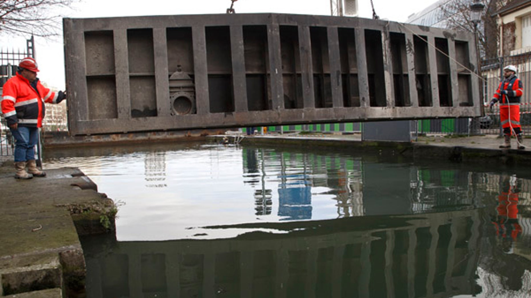 Jan. 4, 2016: Municipal workers guide a lock plate at the Canal-Saint Martin, as it is drained for maintenance in Paris (AP)