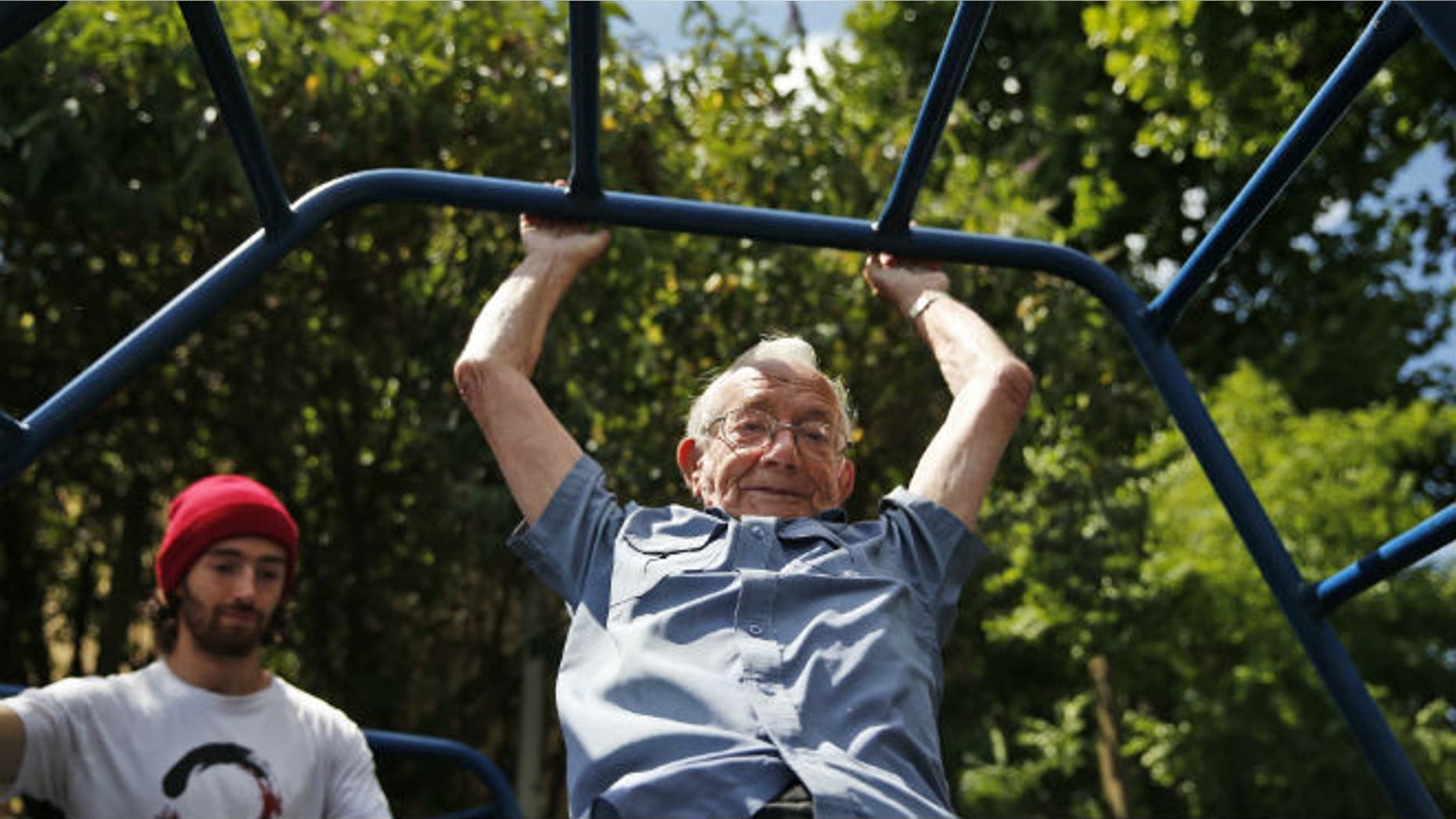 In this Tuesday, June 17, 2014 photo, George Jackson, 85, an army veteran and former boxer swings on monkey bars as he participates at a parkour class for elderly people at a park in south London. (AP Photo/Lefteris Pitarakis)