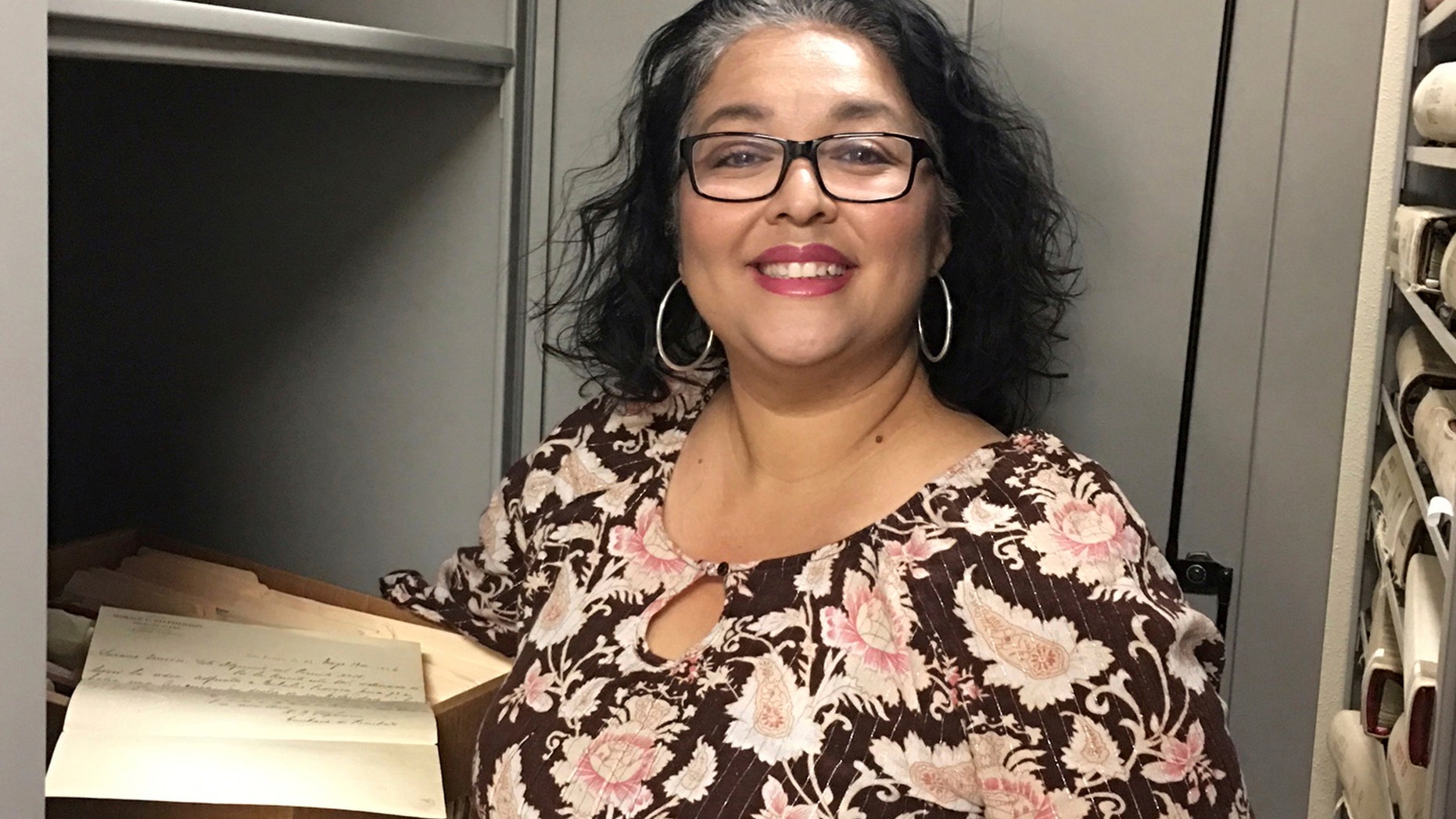 In this photo provided by the Doña Ana County Manager's Office, Records and Filing Supervisor Angelica Valenzuela poses at the Doña Ana County Clerk's Office Friday, May 19, 2017, in Las Cruces, N.M. Valenzuela found a century-old document inside a box of unarchived records that sheds light on the death of the Old West lawman Pat Garrett who gained fame for killing Billy the Kid. (Doña Ana County Manager's Office via AP)