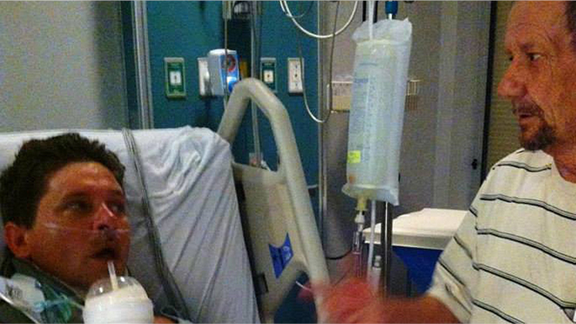 Michael Patterson, left, is joined by his stepfather, Ricky Robinson, at Redmond Regional Medical Center earlier this month. Patterson, 43, severed his spine in a Georgia creek while rescuing a 4-year-old girl from drowning on June 8. Patterson succumbed to his injuries on Friday. (Courtesy: Friends of Mike Patterson)