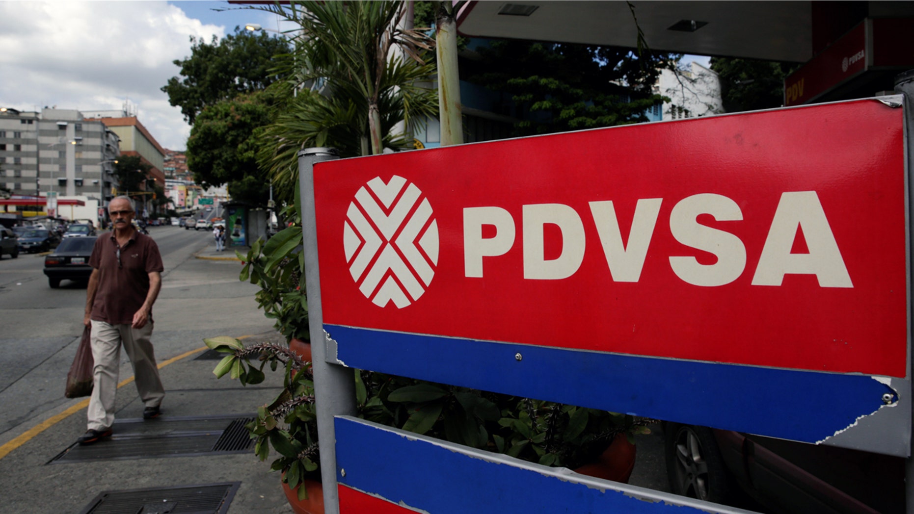 A man walks past the corporate logo of the state oil company PDVSA at a gas station in Caracas, Venezuela December 1, 2017. REUTERS/Marco Bello - RC1F873E1C20