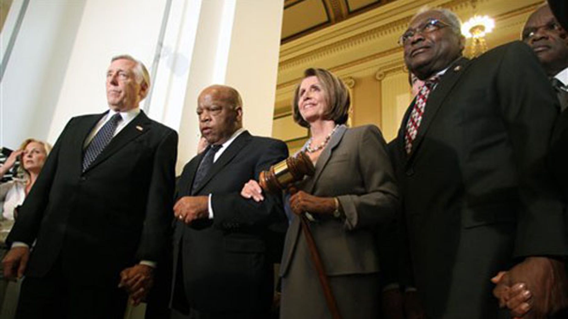 House Speaker Nancy Pelosi holds a large gavel as she emerges from a Democratic caucus meeting with, from left, Reps. Steny Hoyer, John Lewis, and Jim Clyburn on March 21 on Capitol Hill. (AP Photo)