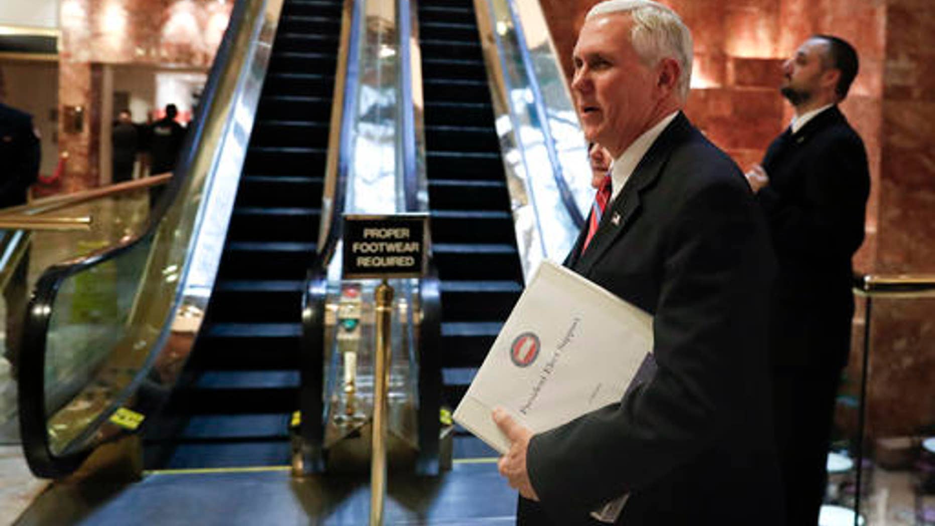 Vice President-elect Mike Pence carries a briefing binder as he arrives at Trump Tower, Tuesday, Nov. 15, 2016, in New York.