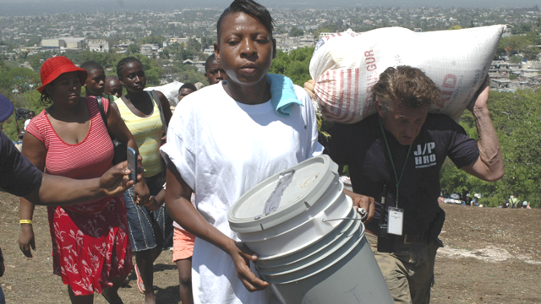 Sean Penn (R) helps to carry the belongings of a earthquake victims during a relocation exercise in Port-au-Prince April 10, 2010. (Reuters)