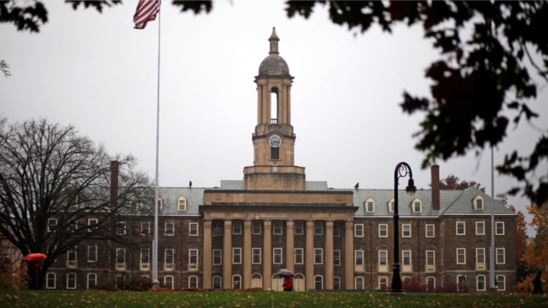 A Penn State student walks in the rain past Old Main on the Penn State main campus in State College, Pa., Wednesday, Oct. 28, 2015. (AP Photo/Gene J. Puskar)