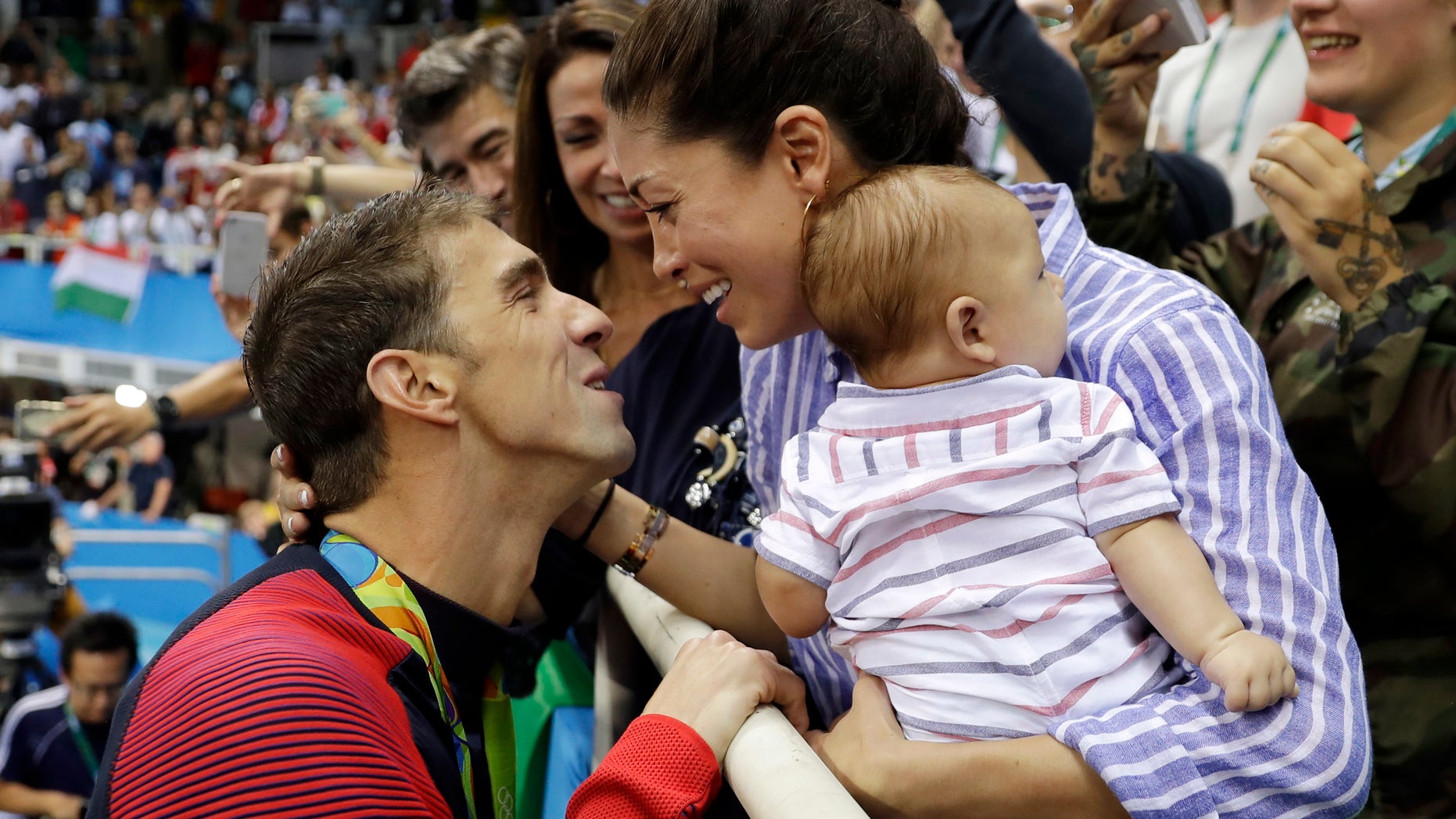 In this Aug. 9, 2016, file photo, United States' swimmer Michael Phelps celebrates winning his gold medal in the men's 200-meter butterfly with his fiance Nicole Johnson and baby Boomer during the swimming competitions at the 2016 Summer Olympics, in Rio de Janeiro, Brazil.