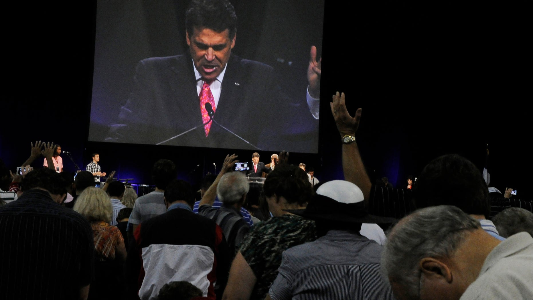 Worshippers pray with Texas Gov. Rick Perry, seen at center and on screen, at The Response, a day long prayer and fast rally, Saturday, Aug. 6, 2011, at Reliant Stadium in Houston.
