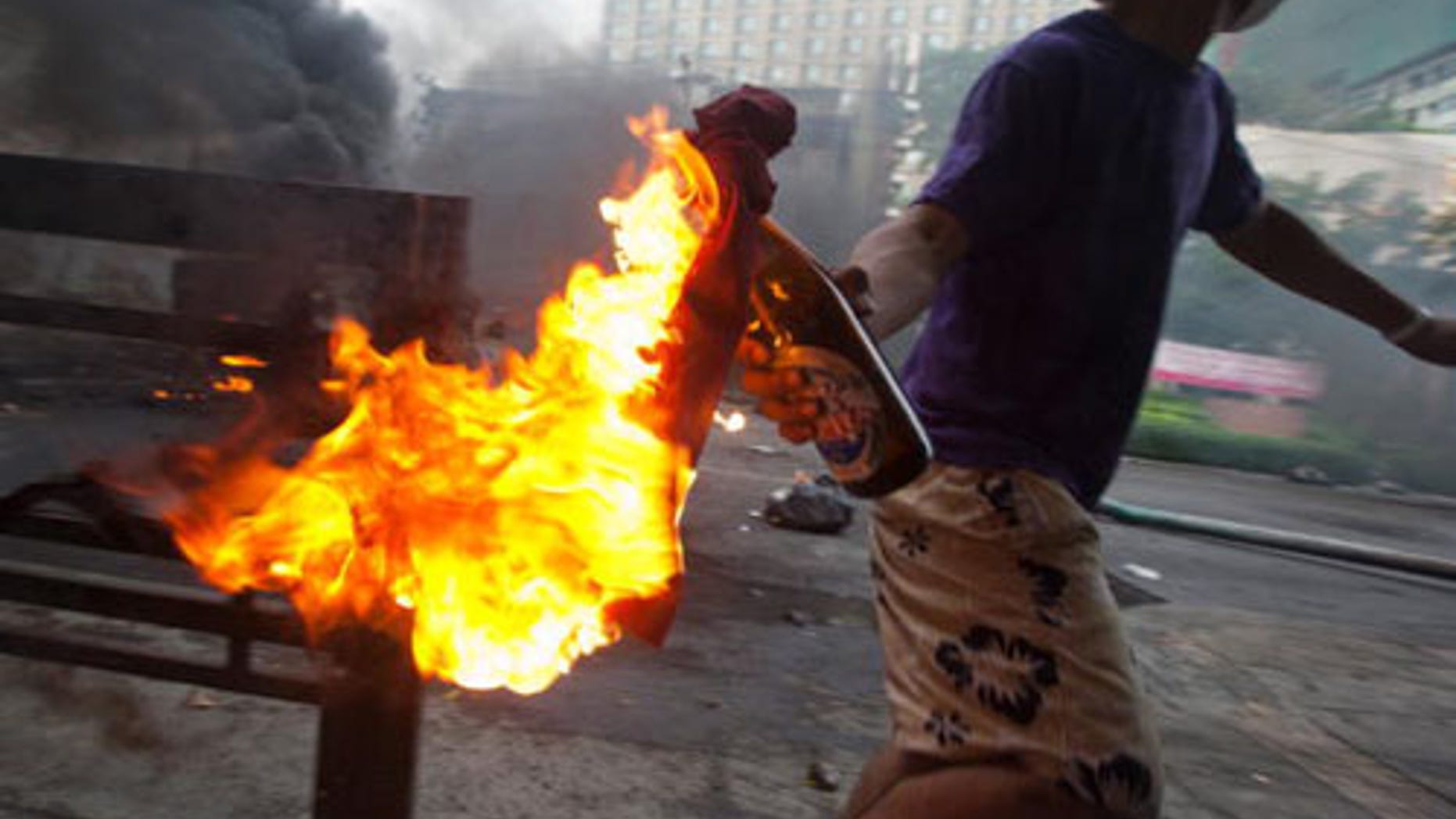 BANGKOK, THAILAND - MAY 16: An anti-government protester 'Red Shirt' throws a molotov cocktail toward Thai security forces as the violence in central Bangkok continues on May 16, 2010 in Bangkok, Thailand. So far at least 154 have been injured and over 20 killed in the clashes as the military and the government launched an operation to disperse anti-government protesters who have closed parts of the city for two months. A state of emergency is in effect that spreads to 17 provinces in the country. The Thai army declared certain protest areas where clashes are taking place as a "Live Fire Zone." (Photo by Athit Perawongmetha/Getty Images)