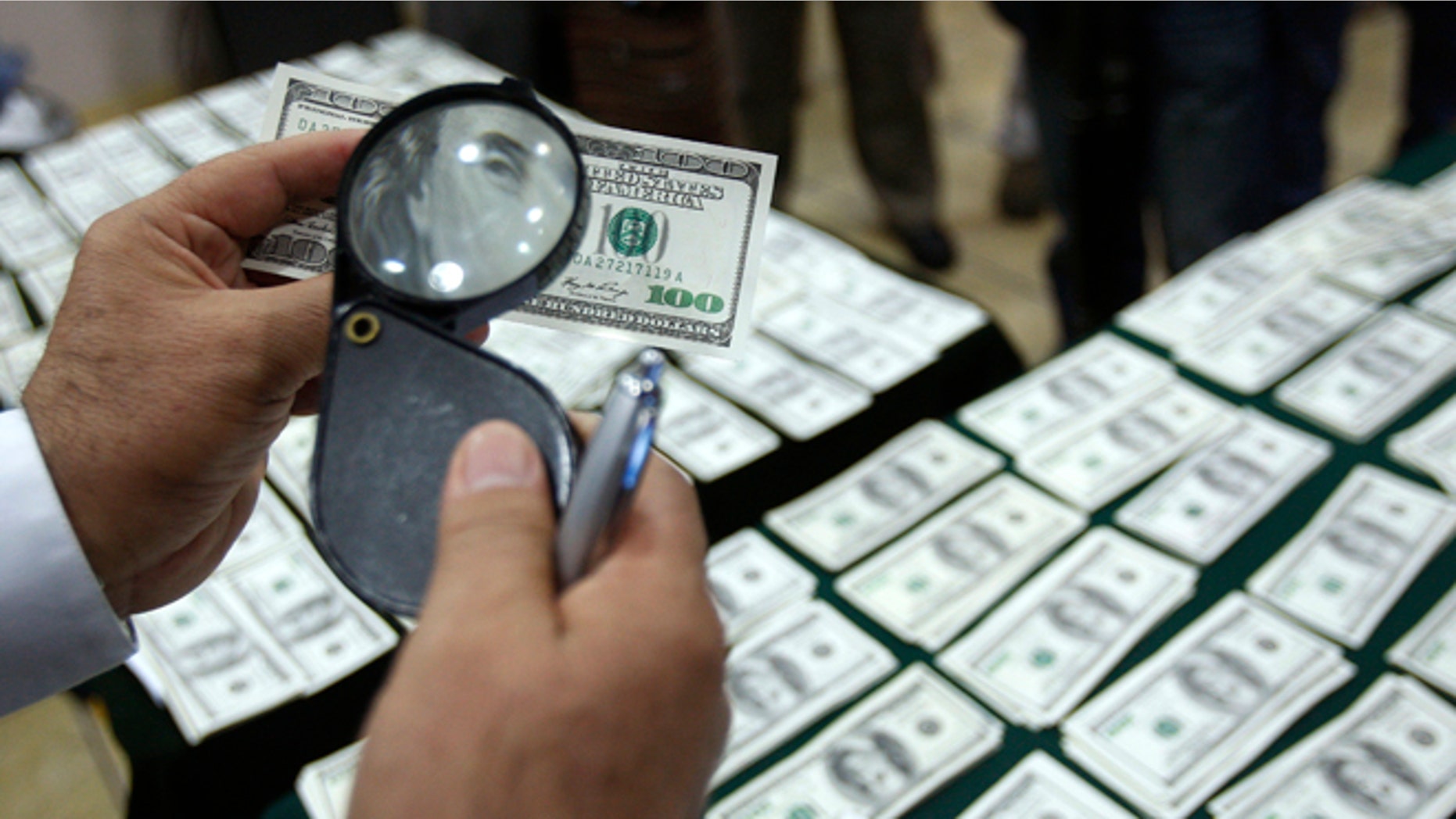 In this Aug. 17, 2012 file photo, a police officer inspects an alleged counterfeit $100 U.S. dollar note during a media presentation in Lima, Peru. With its meticulous criminal craftsmen, cheap labor and, by some accounts, less effective law enforcement, Peru has in the past two years overtaken Colombia as the No. 1 source of counterfeit U.S. dollars, says the U.S. Secret Service, protector of the worlds most widely-traded currency.