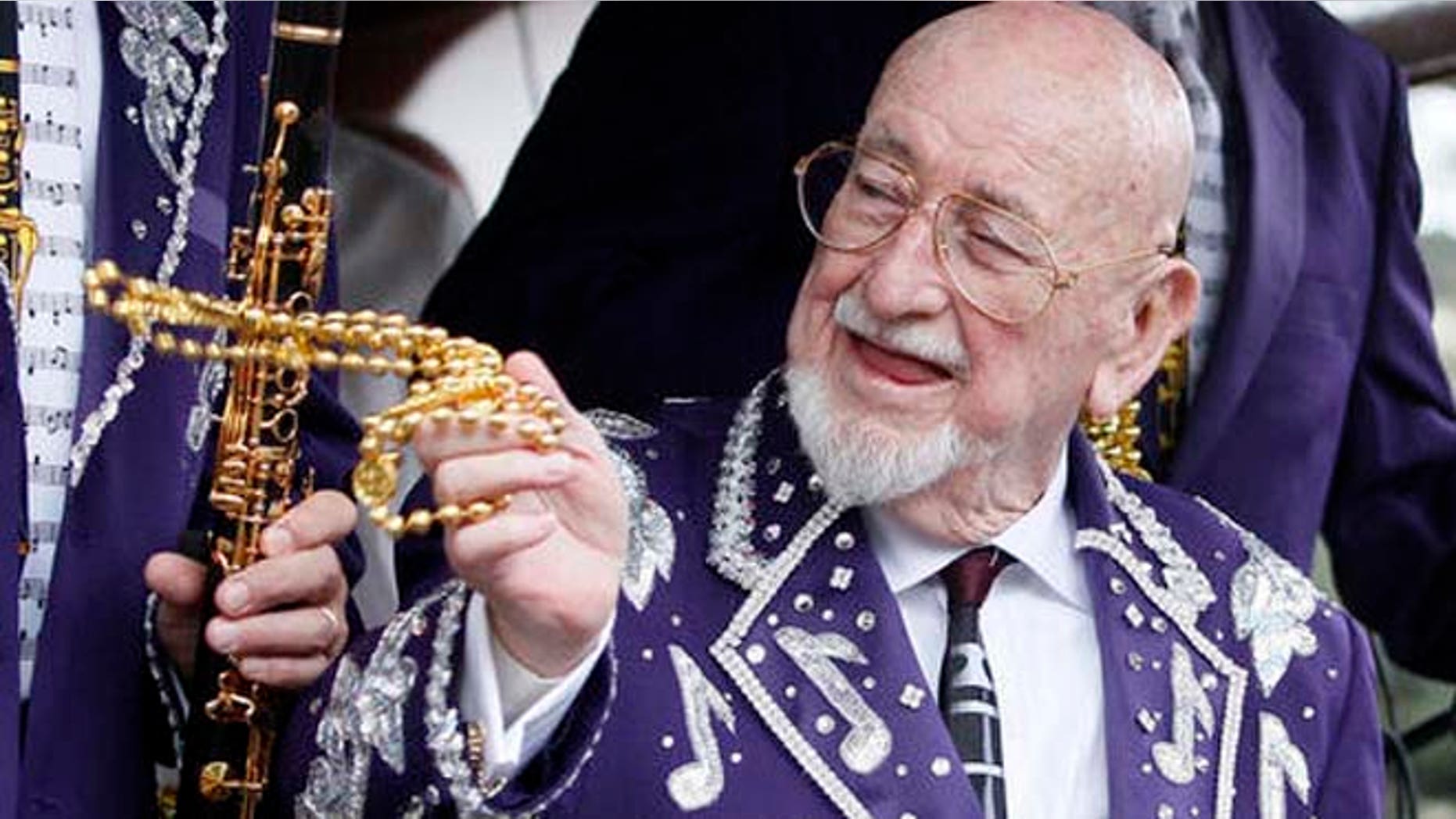 Musician Pete Fountain tosses beads to a reveler from a float as his Half-Fast Walking Club marches down St. Charles Avenue in New Orleans on Mardi Gras Day 2011. (AP Photo/Patrick Semansky)