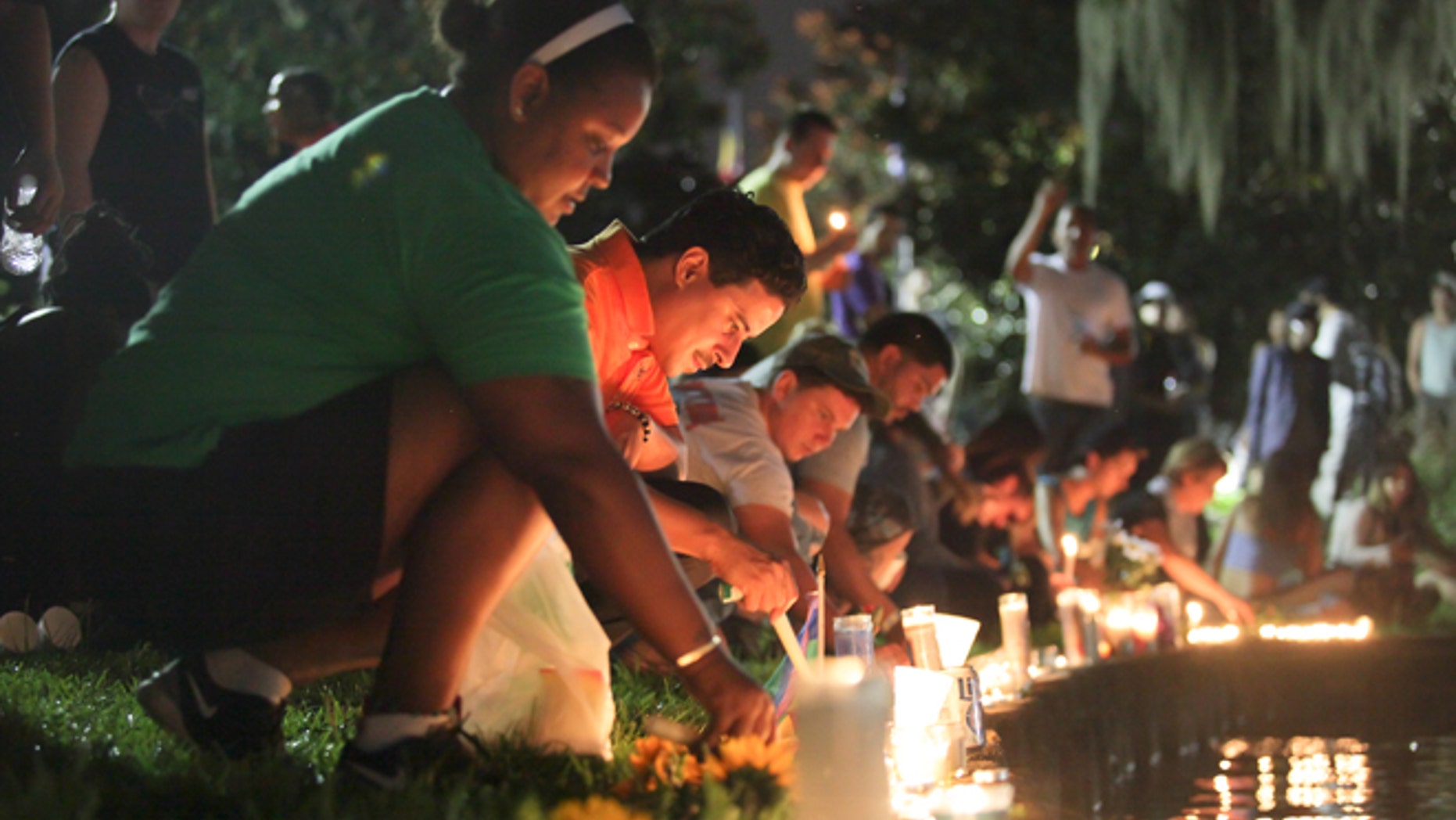 Wendy Frias, from left, and Hector Silva light candles along Lake Eola in Orlando, Sunday, June 12, 2016. The New York natives have made Orlando their home in recent years and came to the vigil for the victims of the Pulse night club tragedy.