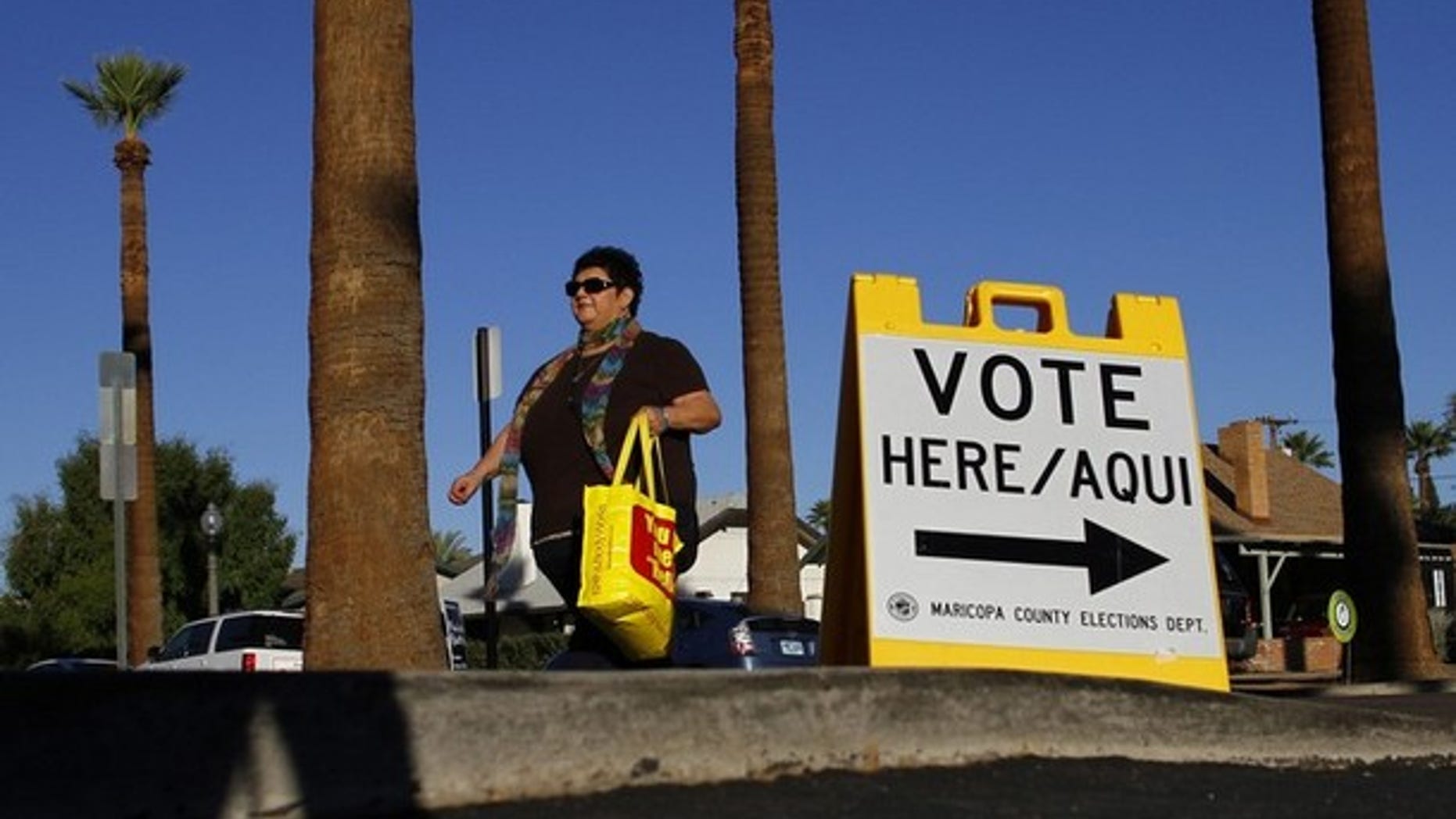 A woman walks past a sign directing voters to a polling place in the Phoenix, Ariz., Nov. 2, 2010.