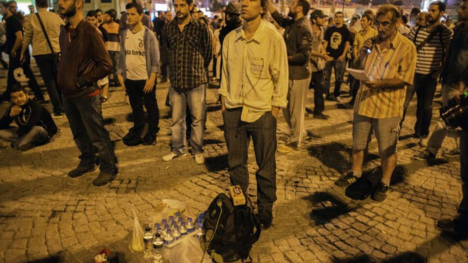 Turkish choreographer Erdem Gunduz (C) stands on Taksim square following what had been a lone protest June 18, 2013. Gunduz stood for several hours unnoticed before his presence on the flashpoint square went viral on the social network Twitter. He was then joined by hundreds of others who in solidarity decided to join his protest by standing for hours on end.