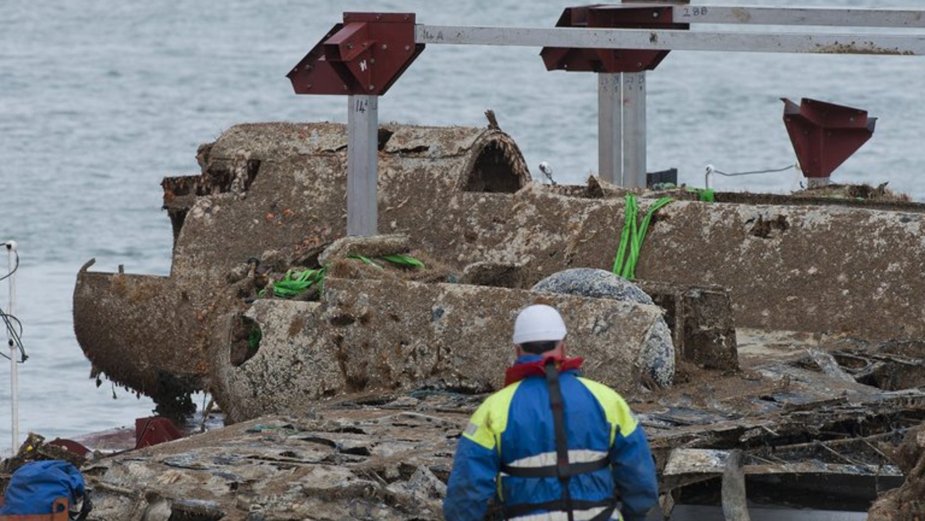 The wreck of a German World War II Dornier Do-17 bomber plane is transported on a barge into Ramsgate harbour on June 11, 2013 following a salvage operation that raised it from the sea bed. British experts began on Tuesday an 18-month task of cleaning the barnacles, silt and seaweed from a rare World War II German bomber plane rescued after more than 70 years on the sea bed.