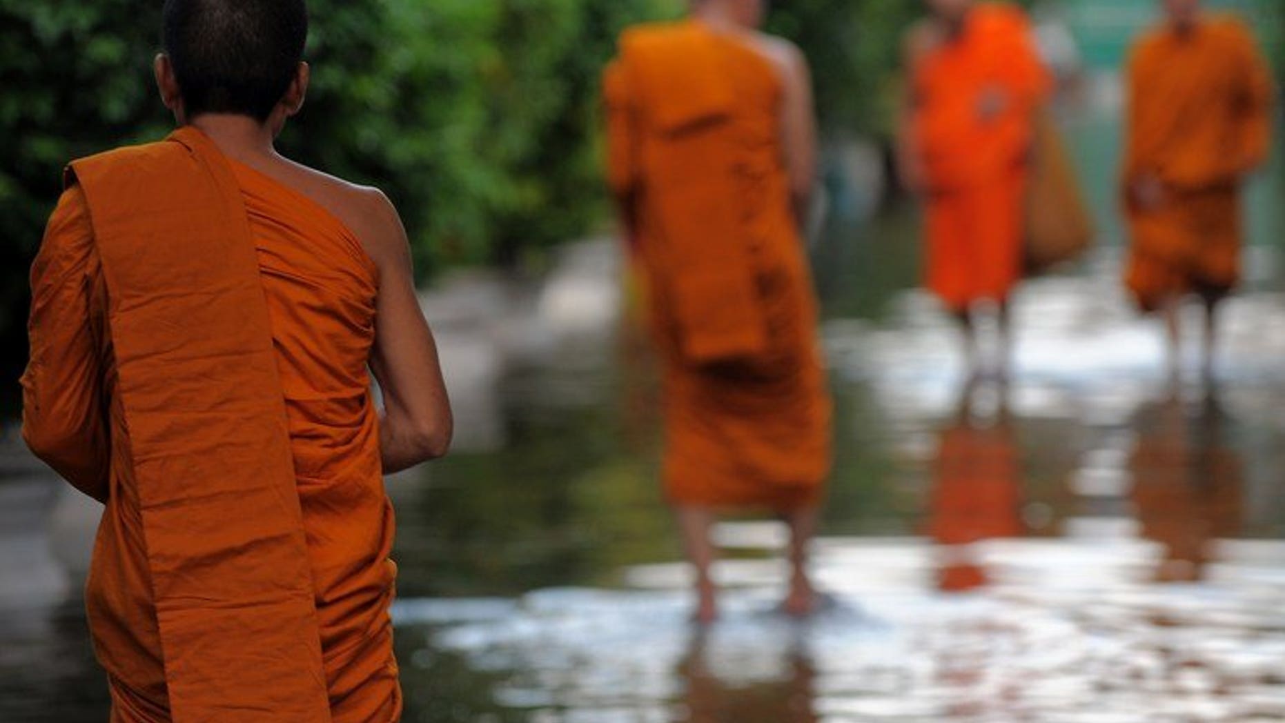 Thai Buddhist monks walk through floodwaters at a pagoda in Bangkok on October 27, 2011. Thai police said Wednesday they had arrested two monks for procuring a 14-year-old boy to perform sexual acts with an abbot, in the latest scandal to shake the kingdom's Buddhist clergy.